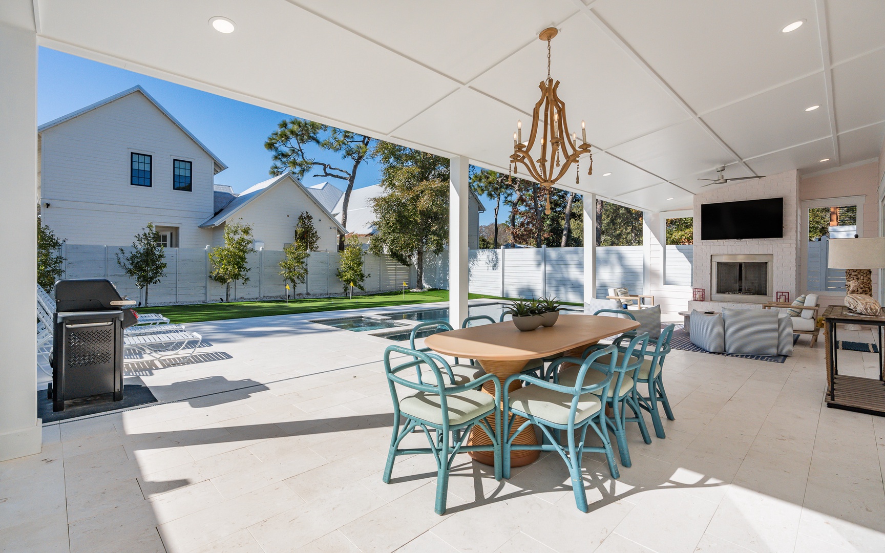 Your elegant covered patio flows seamlessly to the pool, where chandelier dining and cozy seating create perfect indoor-outdoor entertaining.
