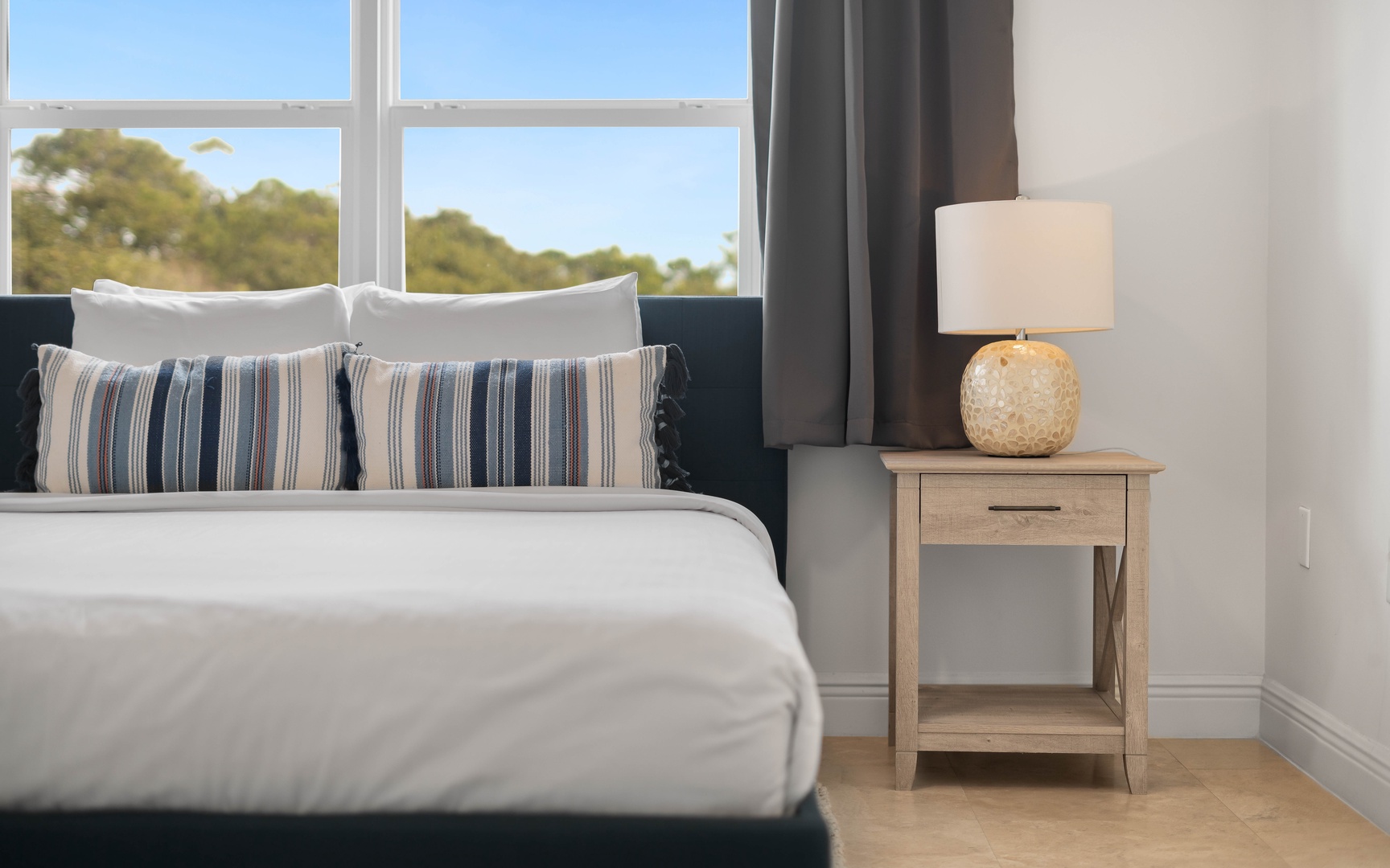 Wake up to peaceful tree views from your comfortable bed with crisp linens and thoughtful touches like the warm bedside lamp.