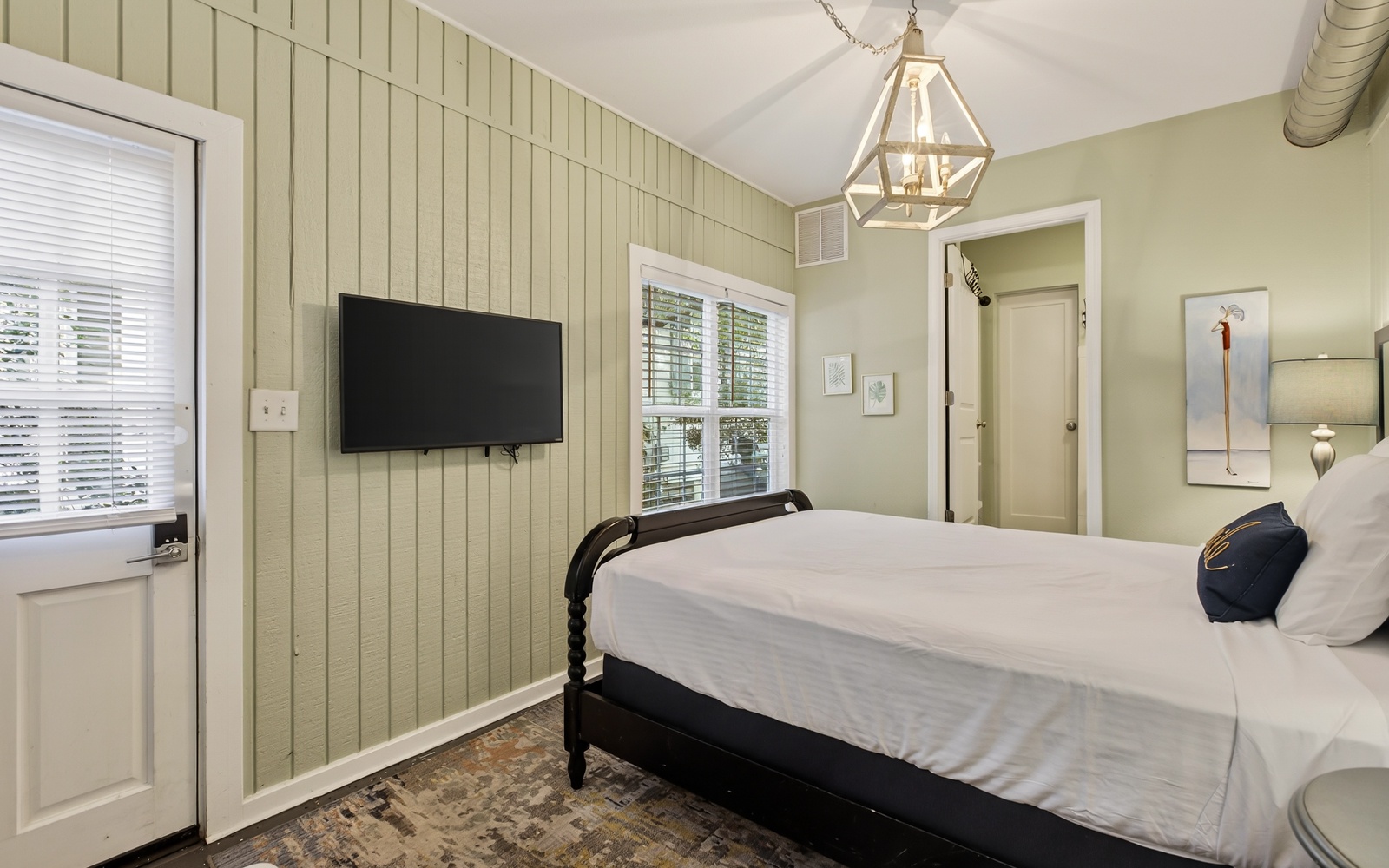 Settle into this charming bedroom with crisp linens, soothing green walls, and modern amenities for your perfect night's rest.