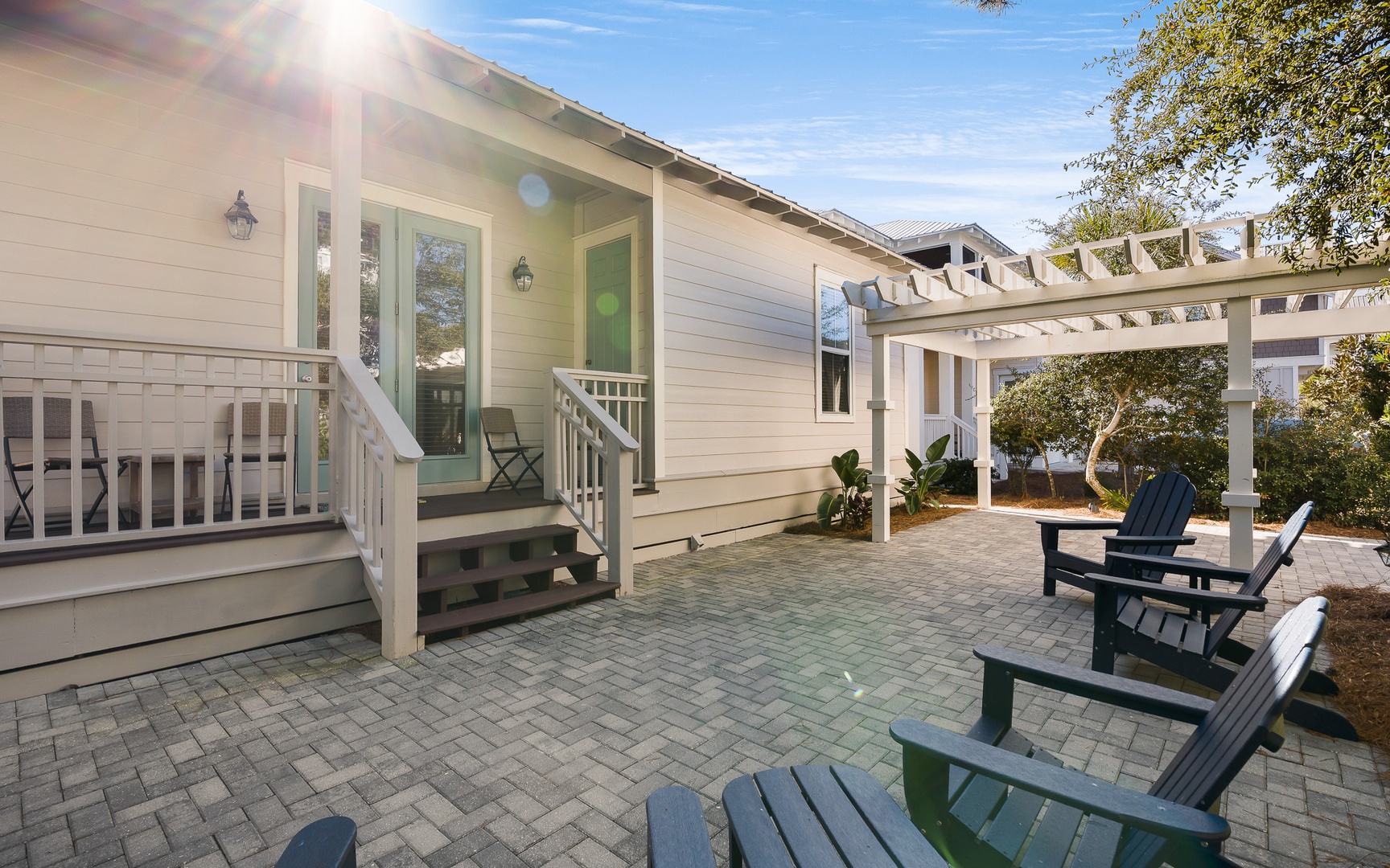 A charming cottage exterior with inviting front porch and spacious paved patio area featuring comfortable outdoor seating.