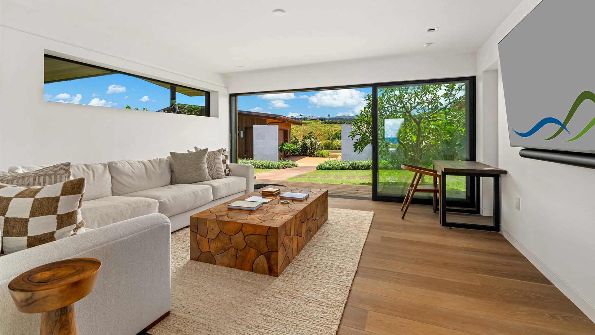 Step into your bright living space where floor-to-ceiling windows frame lush garden views. Sink into the plush sectional and breathe in the island breeze—your peaceful escape awaits.