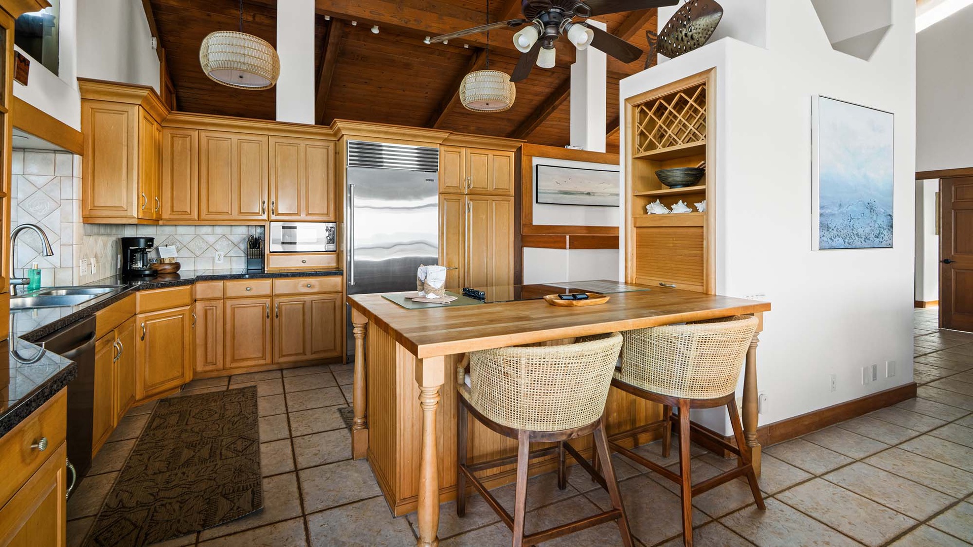 Gather around this warm wood kitchen island where morning coffee and evening conversations flow naturally beneath beautiful woven pendant lights.