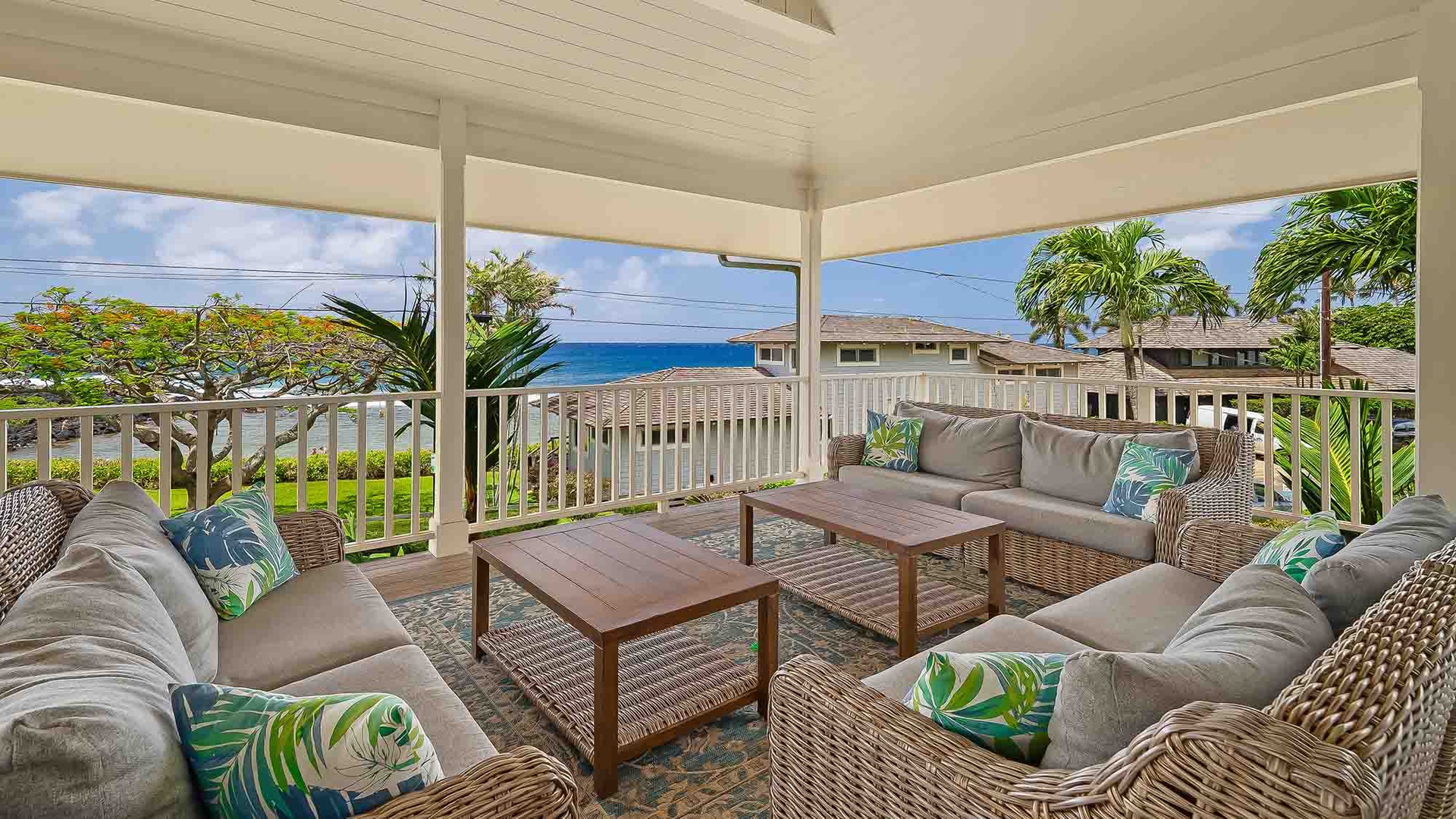 Relax on your private covered lanai with plush seating and stunning ocean views framed by swaying palms—your perfect Hawaiian retreat awaits.