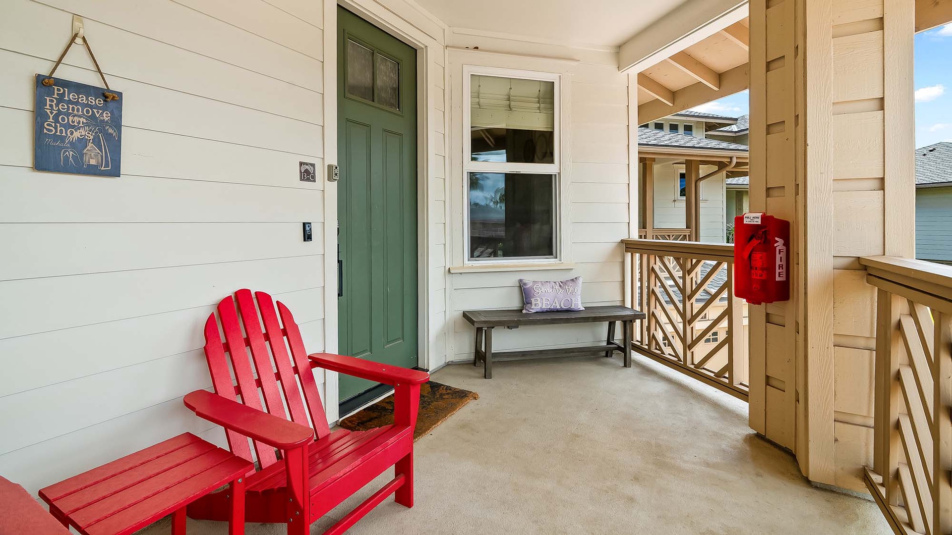 A cheerful red Adirondack chair and bench welcome you at the front door, setting a relaxed, beachy tone before you even step inside.