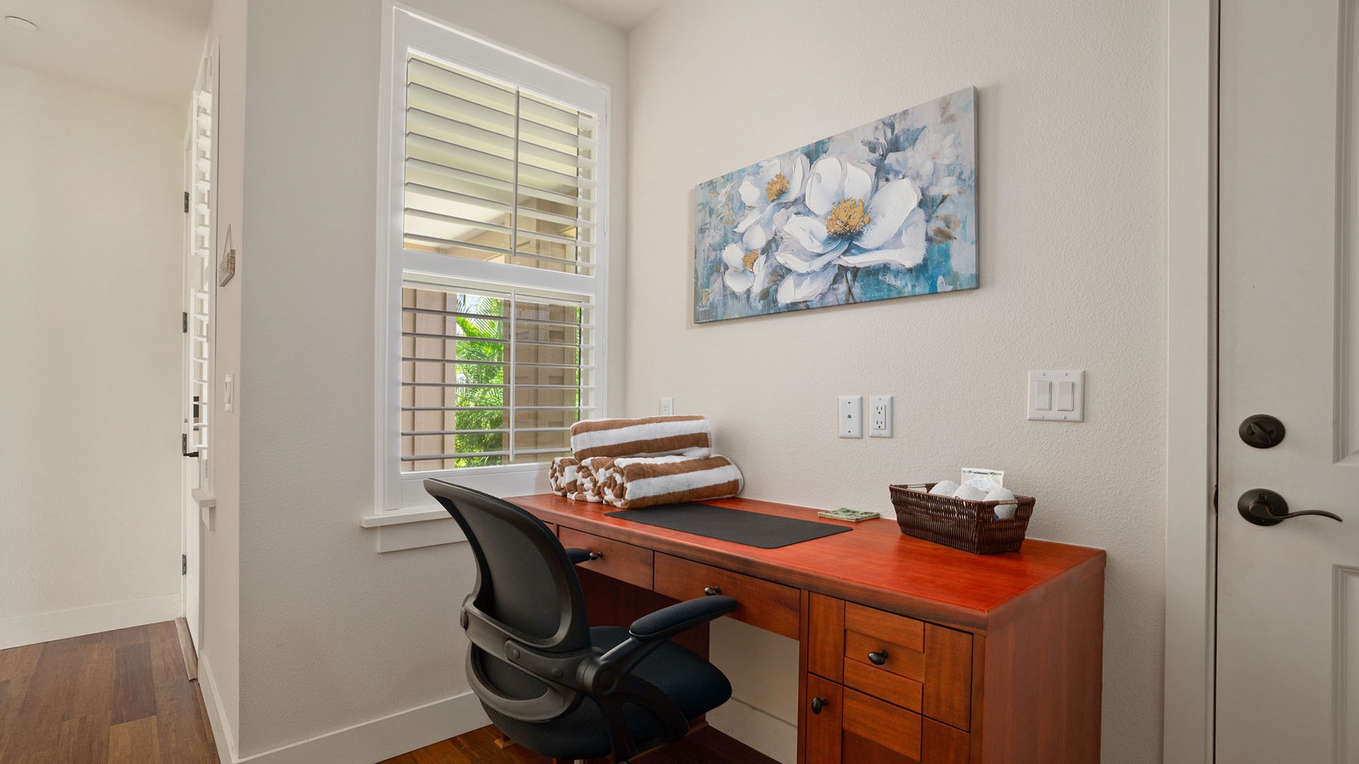Your dedicated workspace awaits with a rich wooden desk, ergonomic chair, and natural light streaming through plantation shutters—perfect for staying productive during your stay.