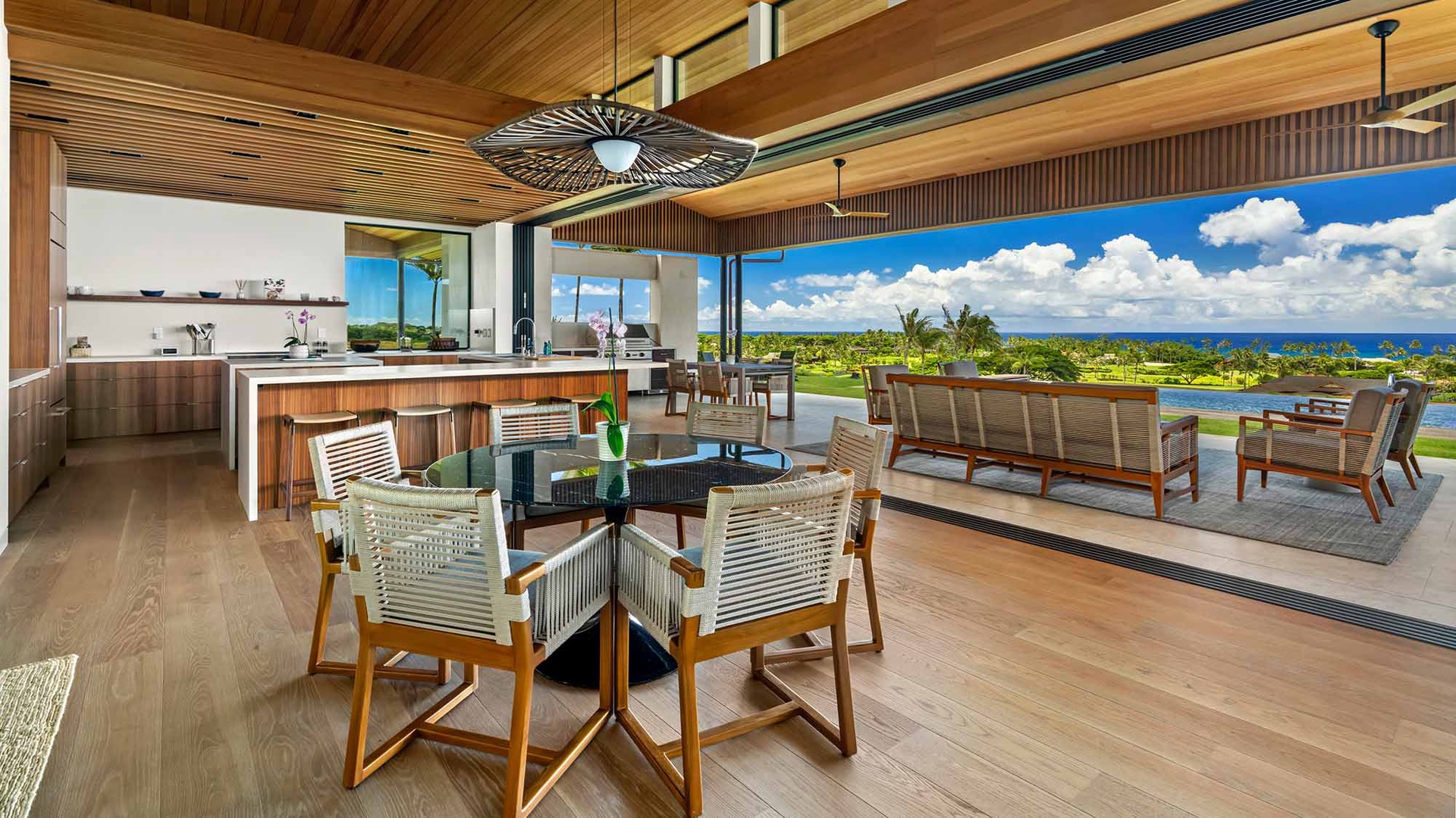 Sweeping ocean and garden vistas stretch across the horizon from this open-plan living space, where warm wood tones and breezy tropical design invite you to relax and soak in paradise.