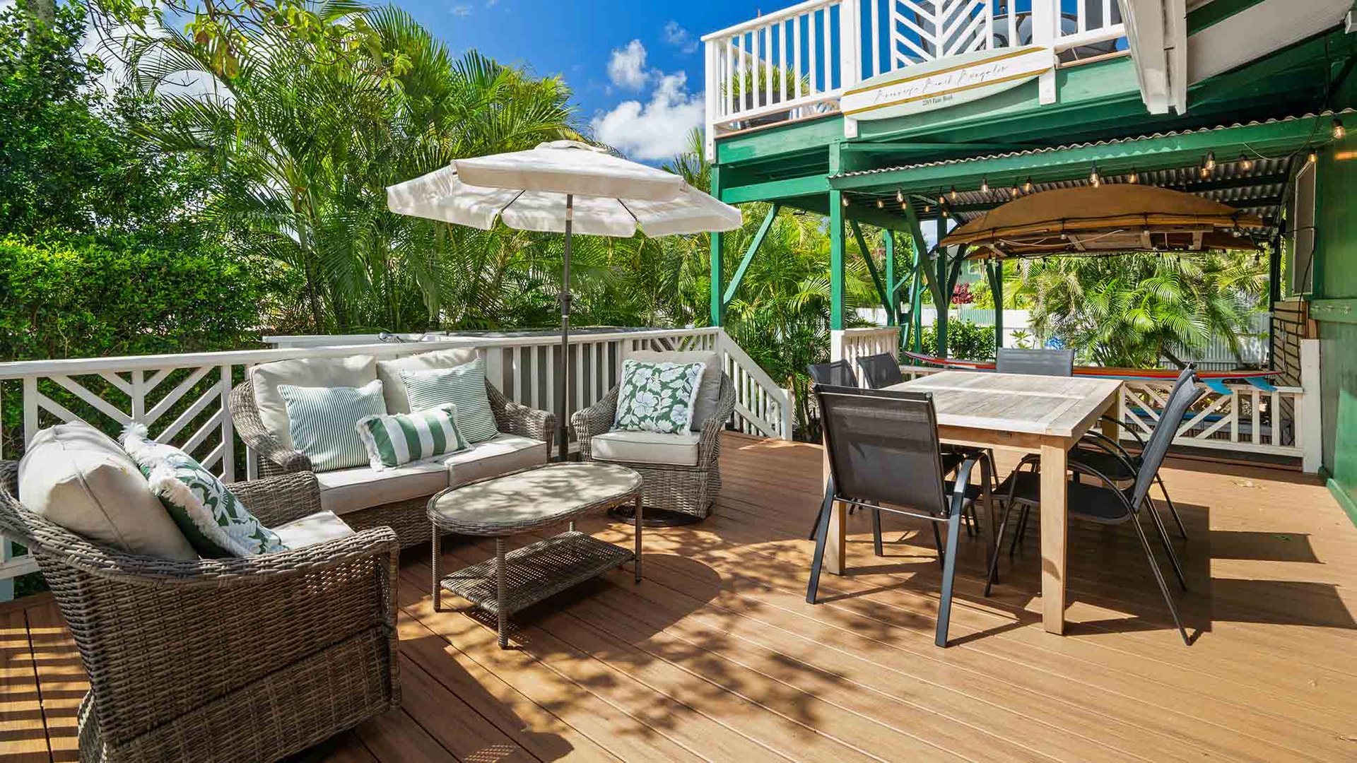 Step out onto your spacious private deck, where tropical palms frame a sunlit lounge and dining area perfect for morning coffee or evening meals under the island sky.