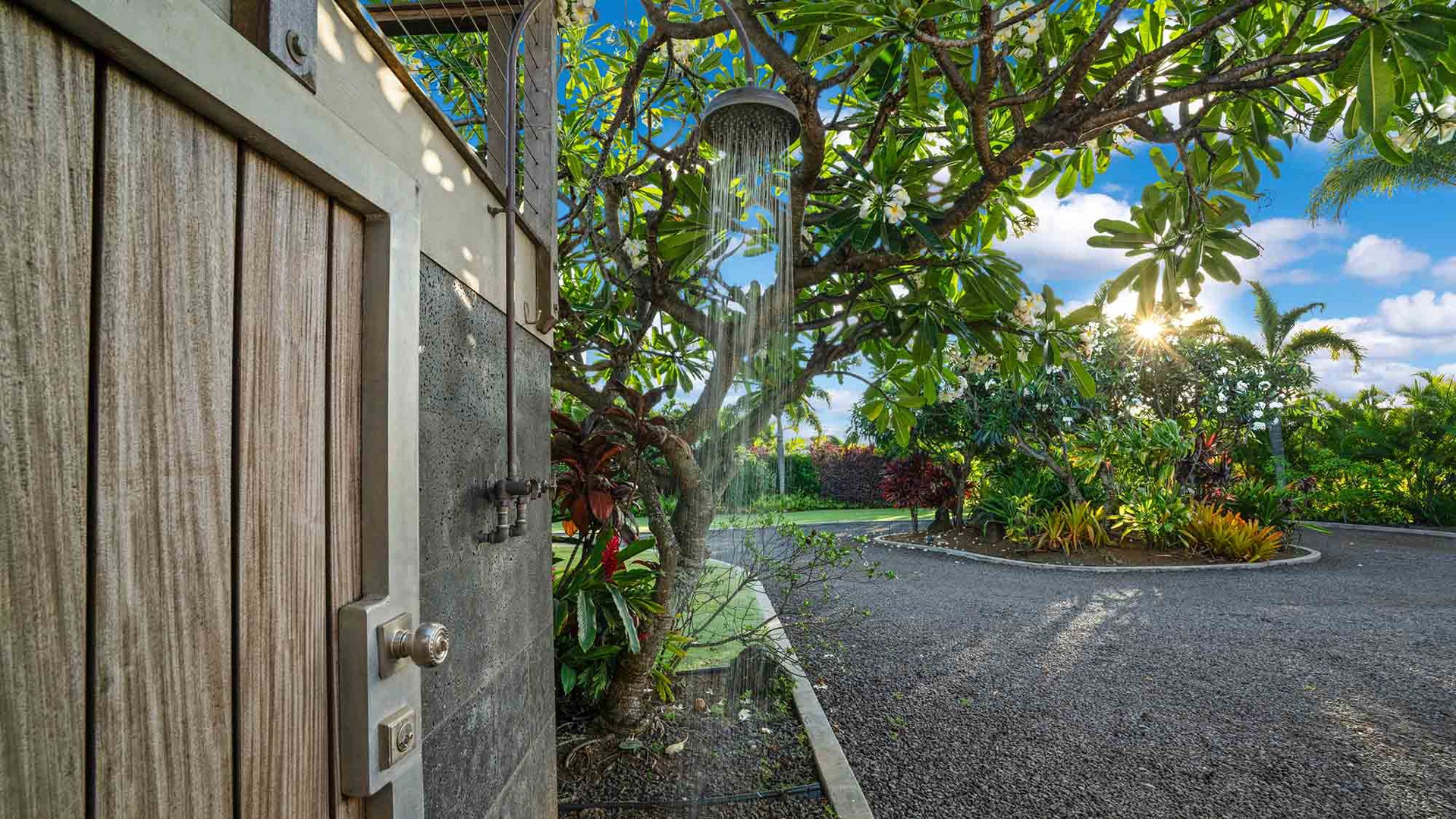 The property features a private outdoor shower nestled among lush tropical landscaping, offering a refreshing rinse after a day of island adventures beneath open skies and swaying palms.