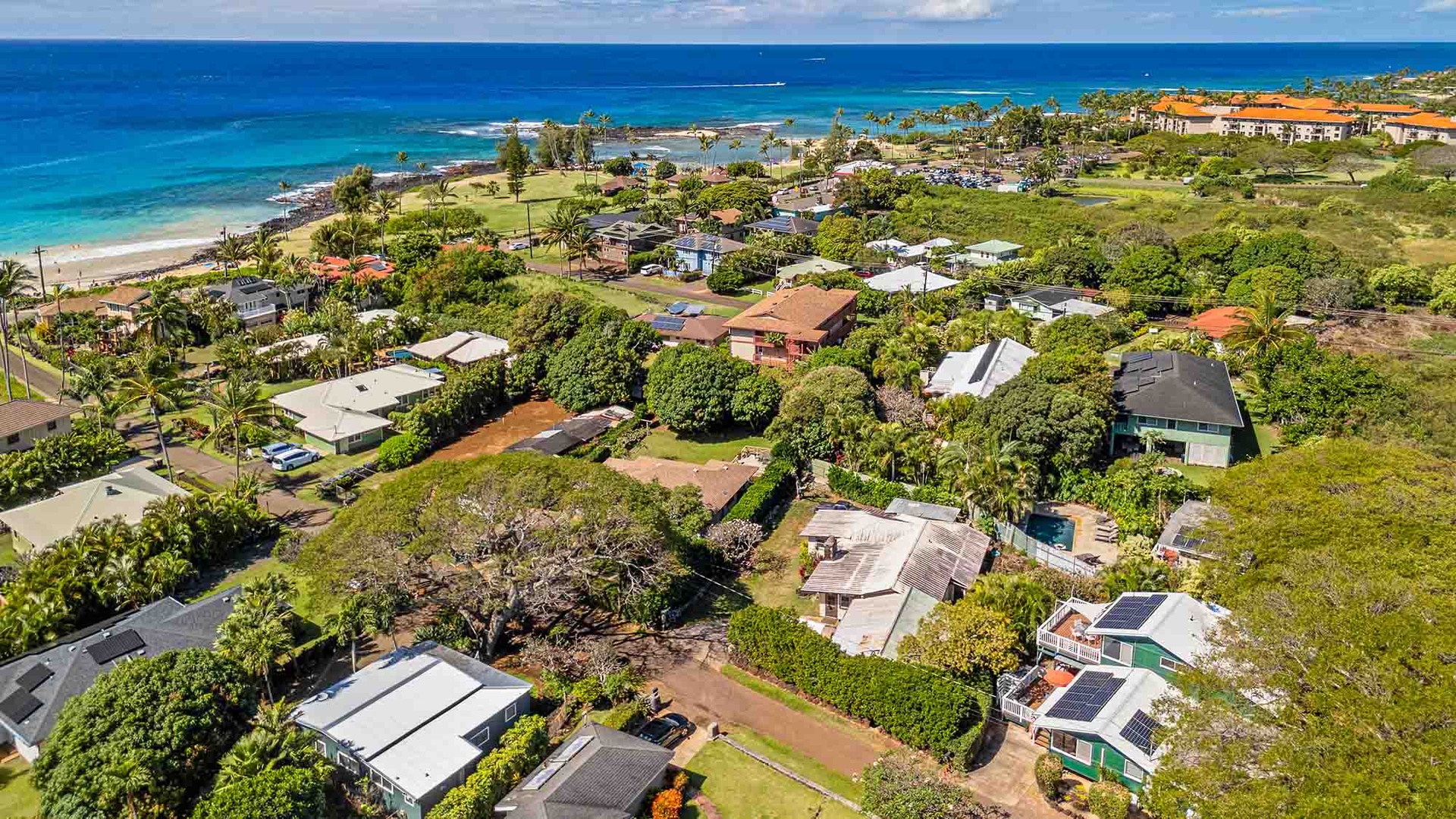 Stunning aerial view of a tropical beachfront community with pristine turquoise waters and lush vegetation.