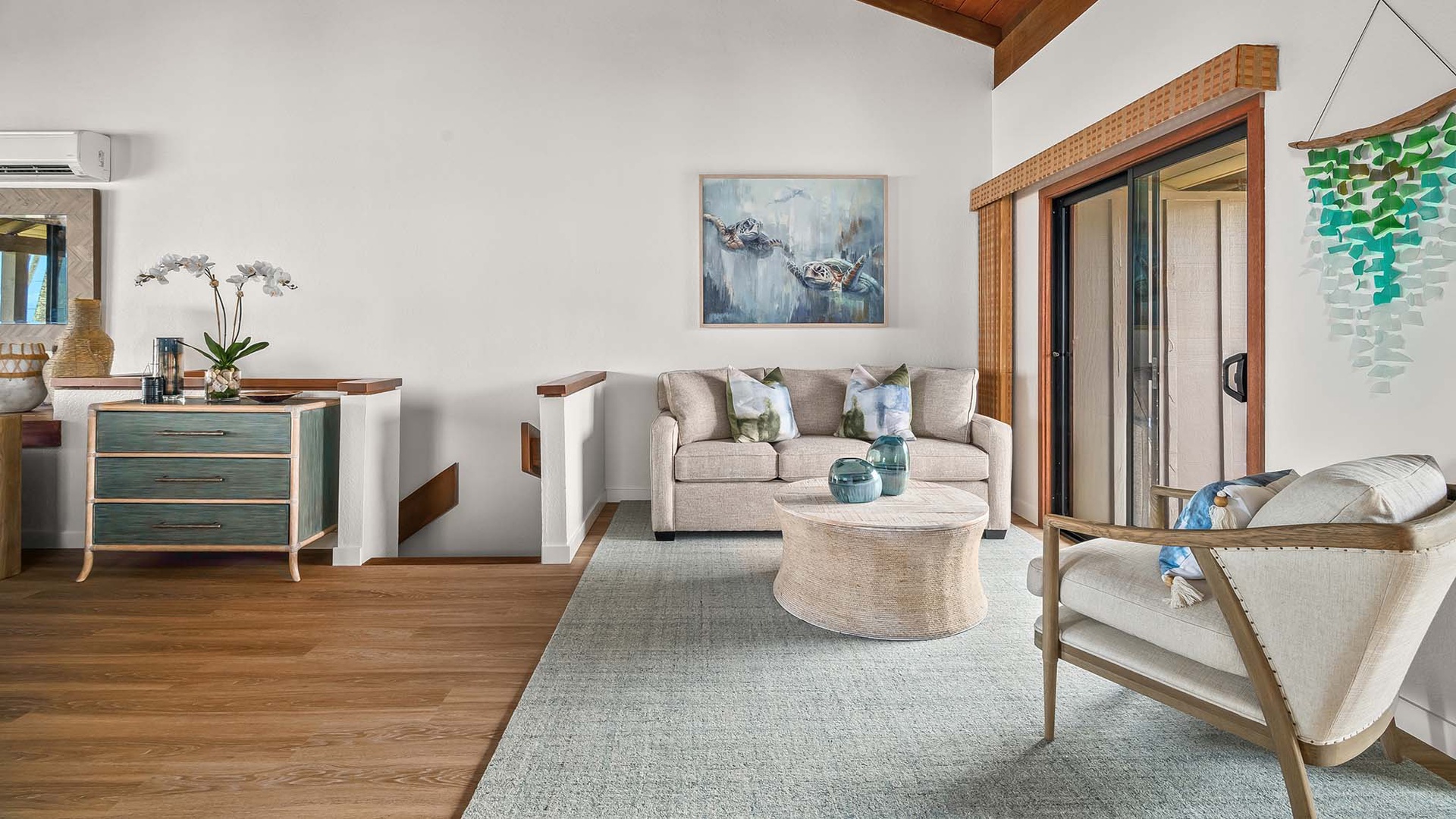 Your bright, airy living room blends coastal charm with modern elegance. Sink into plush seating, admire curated artwork, and let natural light pour through open doors to your private outdoor space.