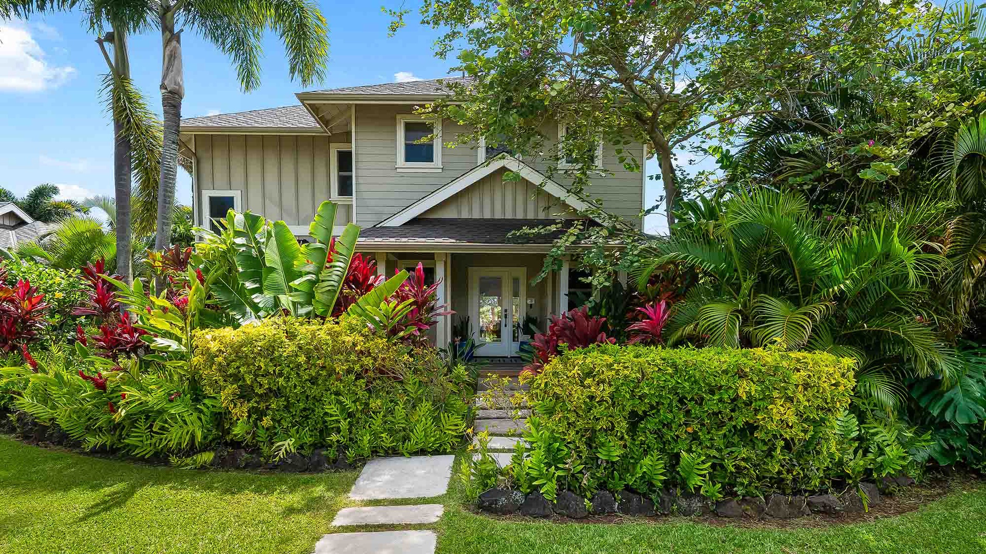 This two-story vacation rental is set in lush tropical landscaping with vibrant palm trees, colorful tropical plants, and a manicured lawn greeting your arrival.