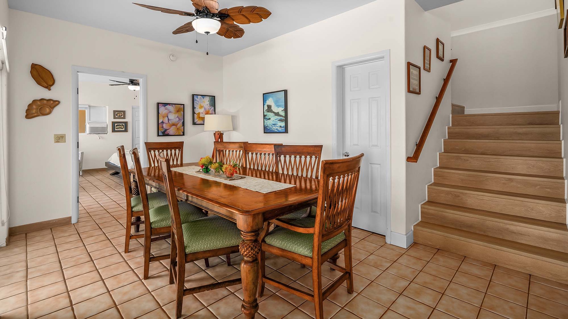Gather around the dining table for shared meals and conversation in this inviting, tropical-accented space with easy access to the kitchen and upper floors.