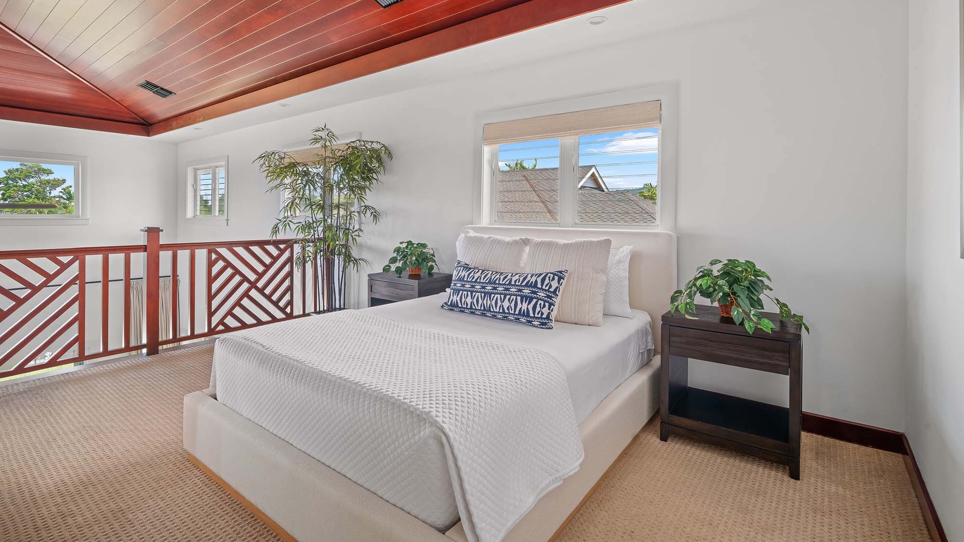 Unwind in your serene loft bedroom, where a plush bed awaits beneath striking wood ceilings. Natural light pours through large windows, while lush greenery adds a refreshing touch to your tropical escape.