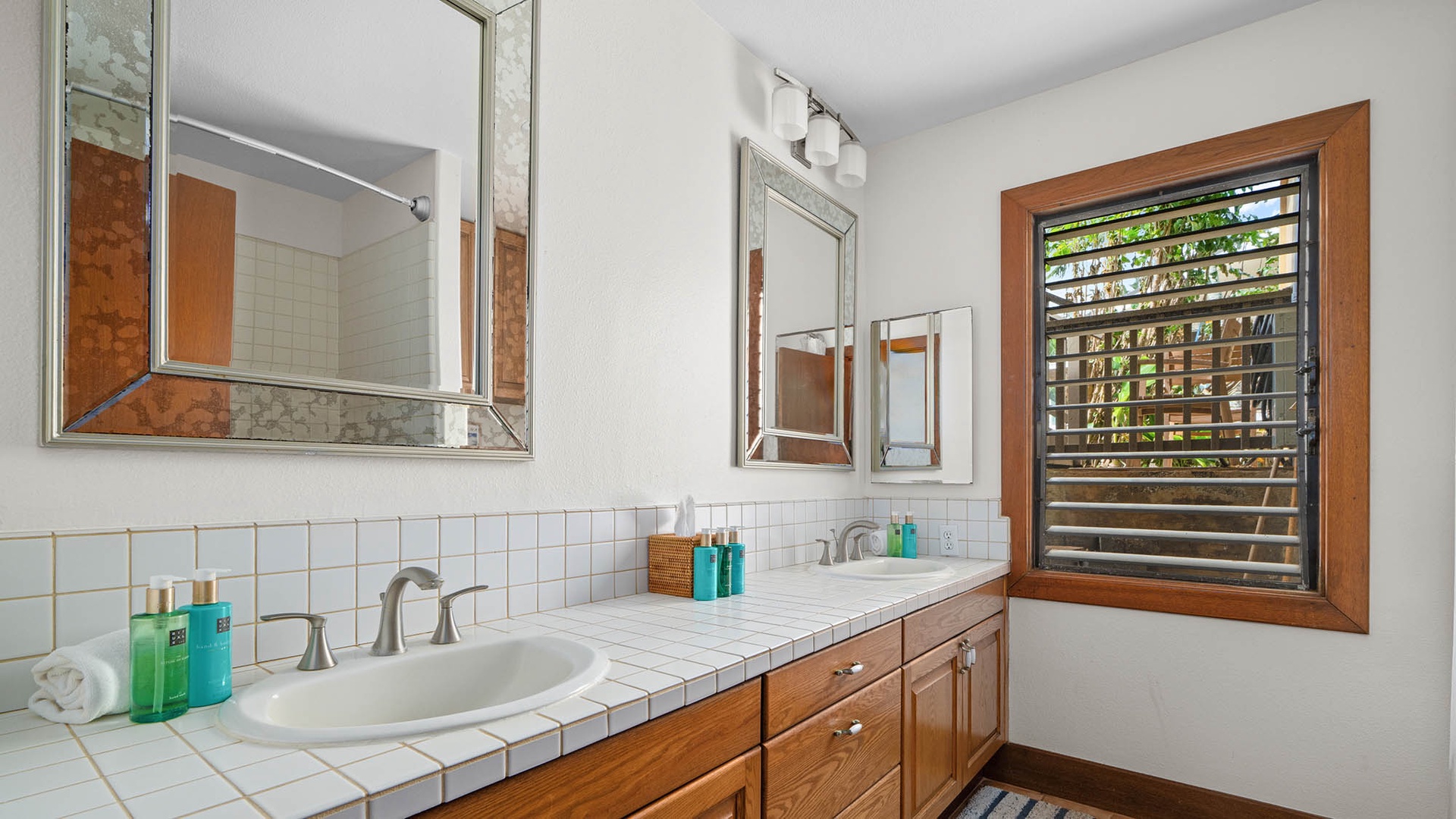 Freshen up in your bright bathroom with dual vanities and tropical views through the louvered window.