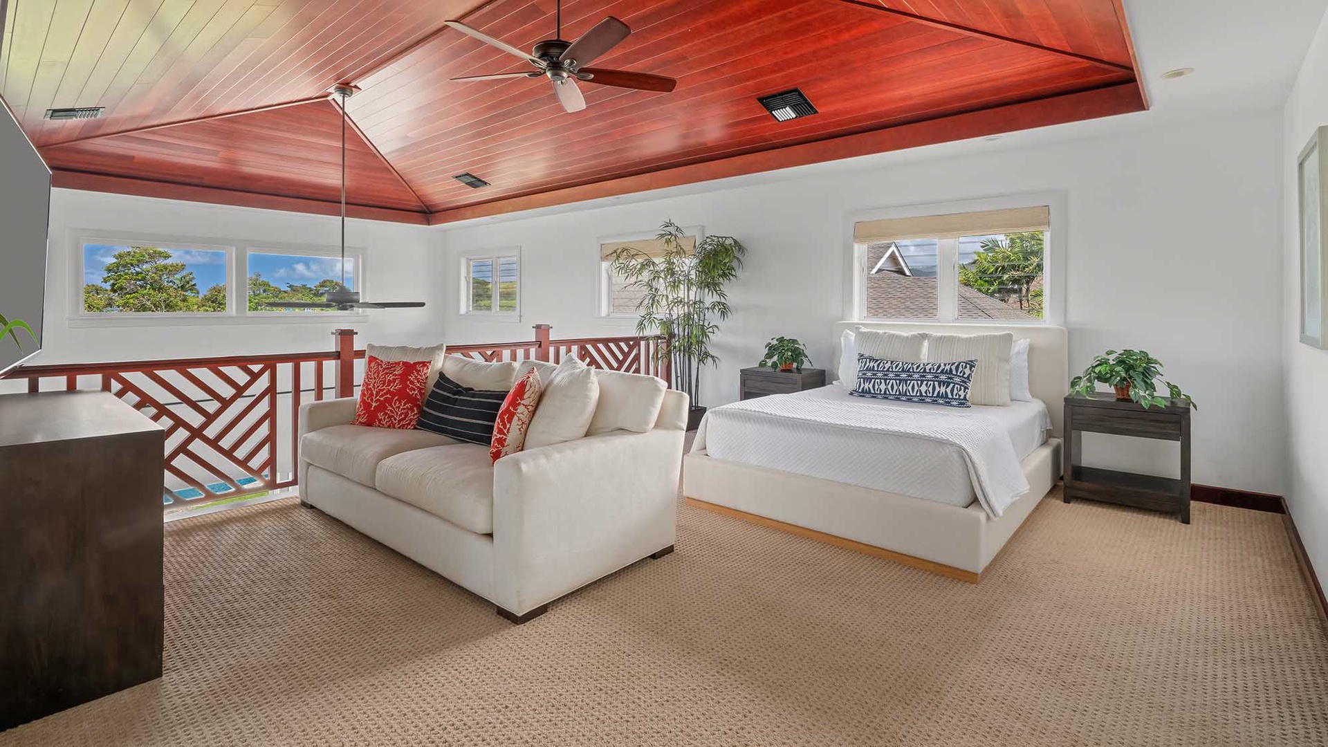 Unwind in your lofted bedroom with vaulted wooden ceilings, a plush bed, and a cozy lounge area. Natural light pours through large windows, inviting you to relax in comfort and style.
