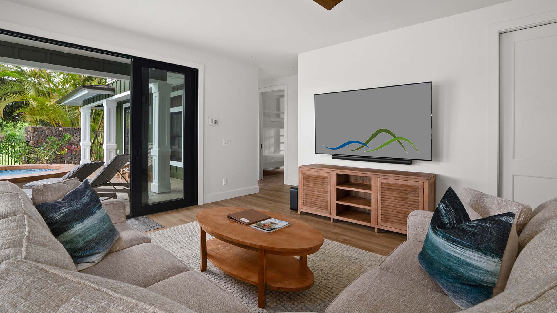 Relax in your stylish living room with plush seating, entertainment center, and tropical garden views through sliding doors.