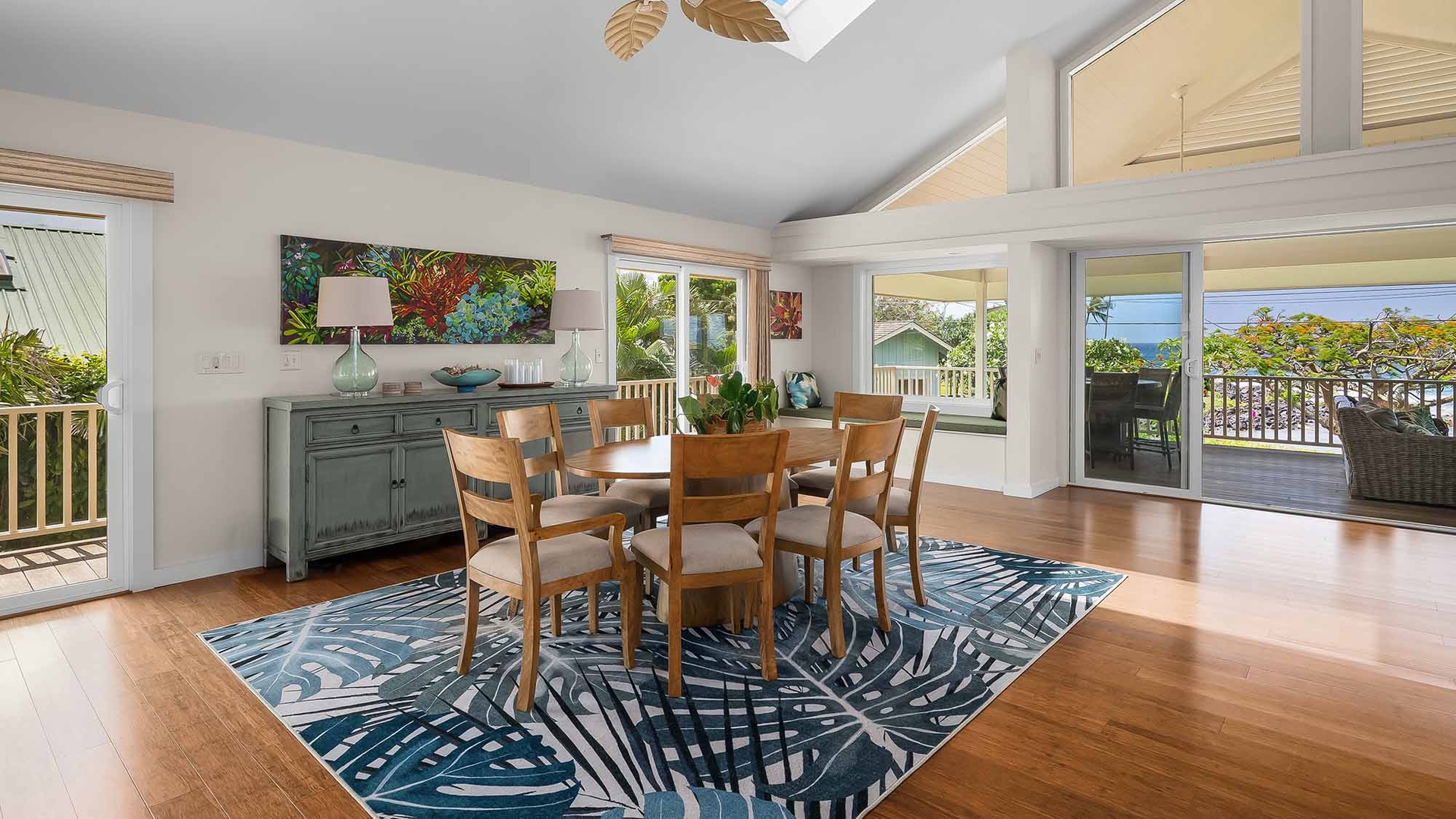Gather around the tropical dining space where warm wood floors meet ocean views. Natural light pours through expansive windows, framing the turquoise sea beyond your balcony.