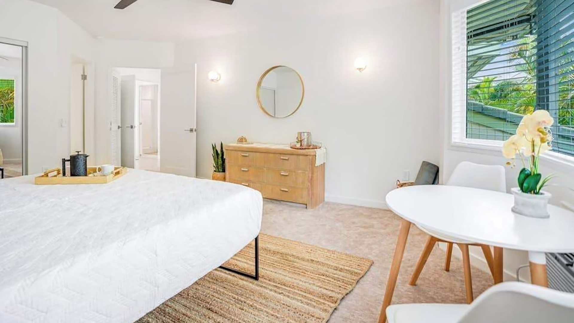 Wake up in this bright, airy bedroom where white linens and natural wood tones create a peaceful retreat. Your morning coffee tastes better at the cozy table by the window.