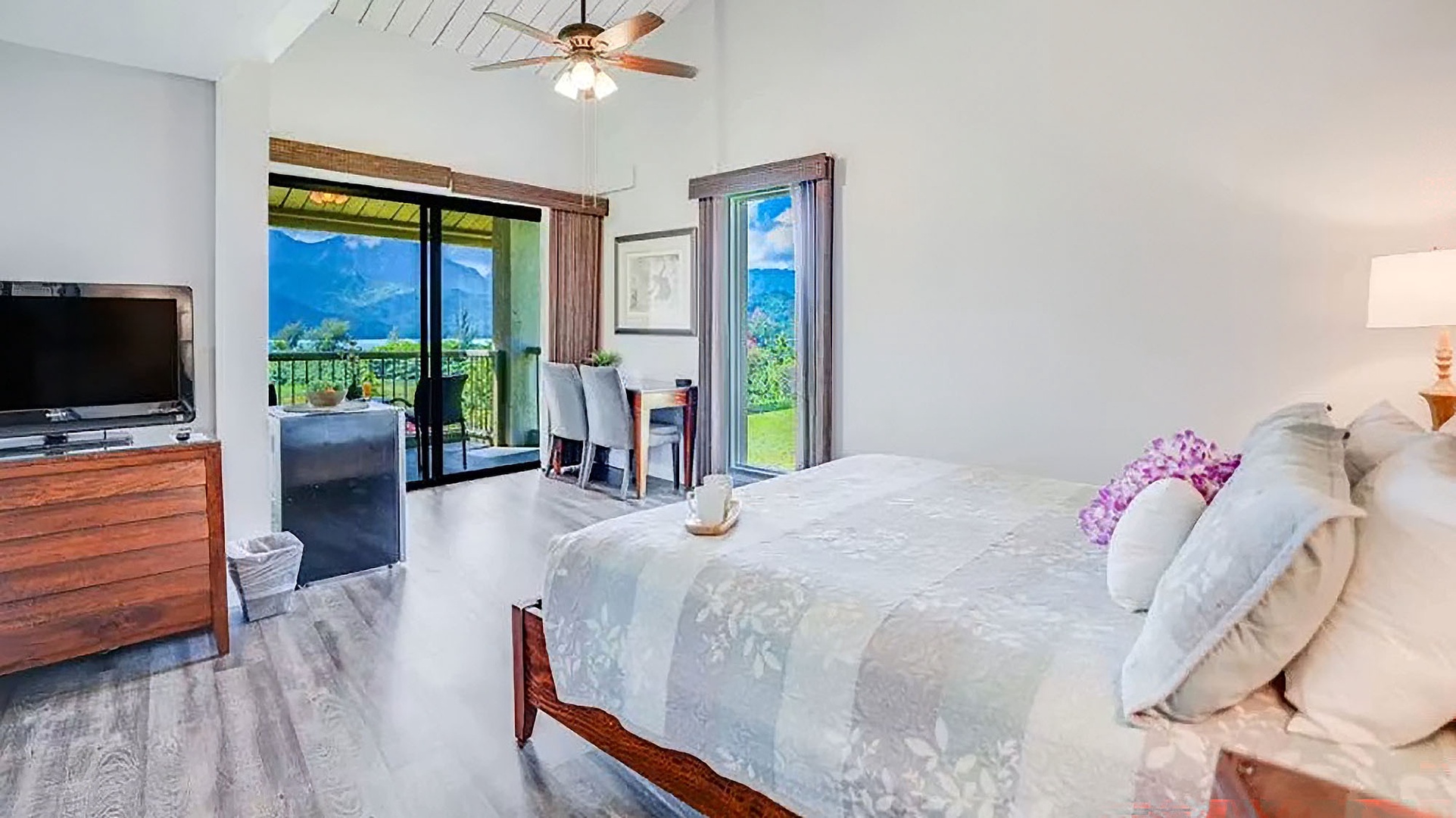 Step into your serene bedroom retreat where soft natural light fills the room and sweeping mountain views greet you through glass doors. The vaulted ceiling and plush bedding invite pure relaxation after a day of island exploring.