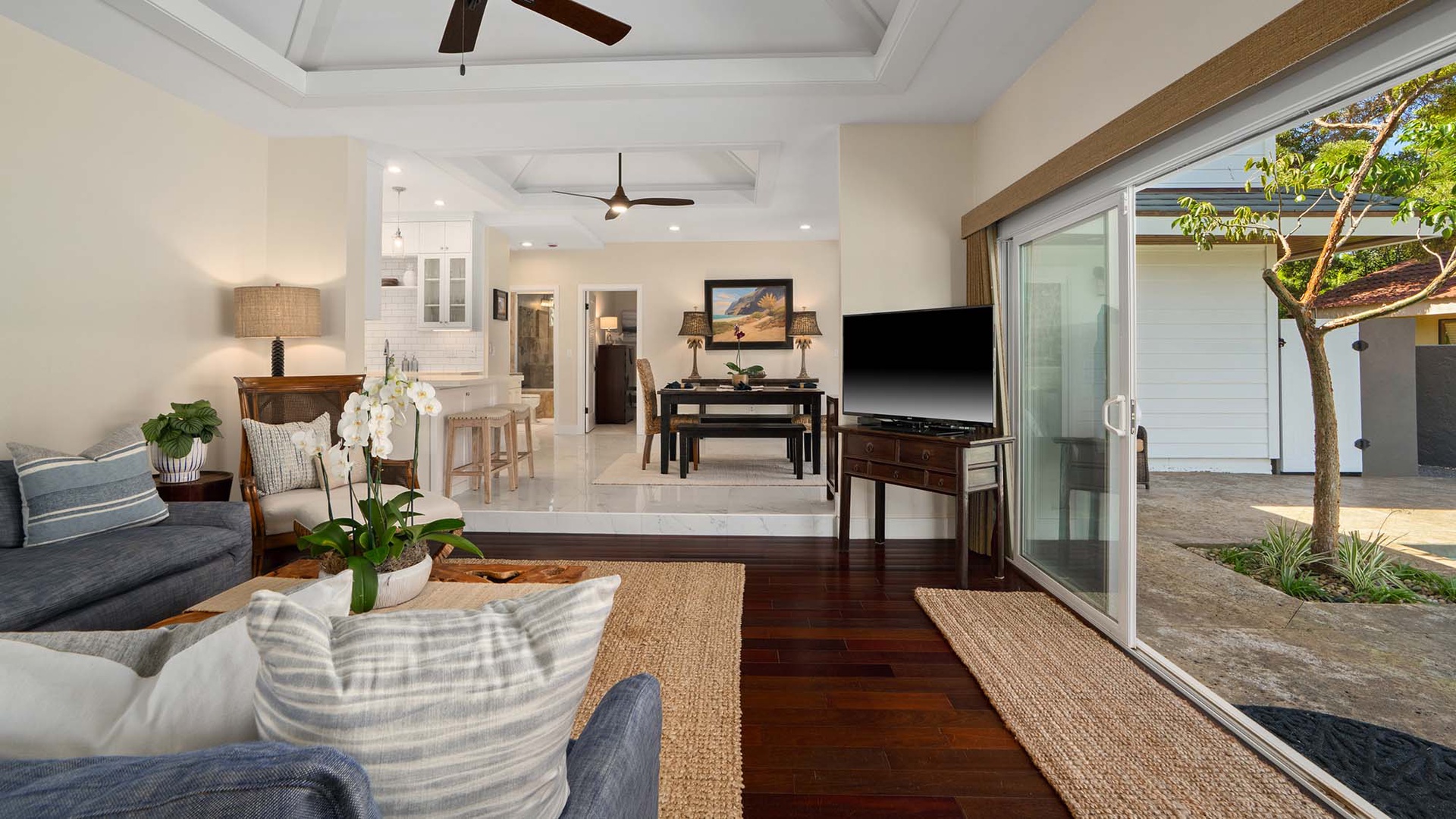 Step into your bright, breezy living space where rich wood floors meet soft coastal textures. Slide open the glass doors to seamlessly blend indoor comfort with your private courtyard oasis.