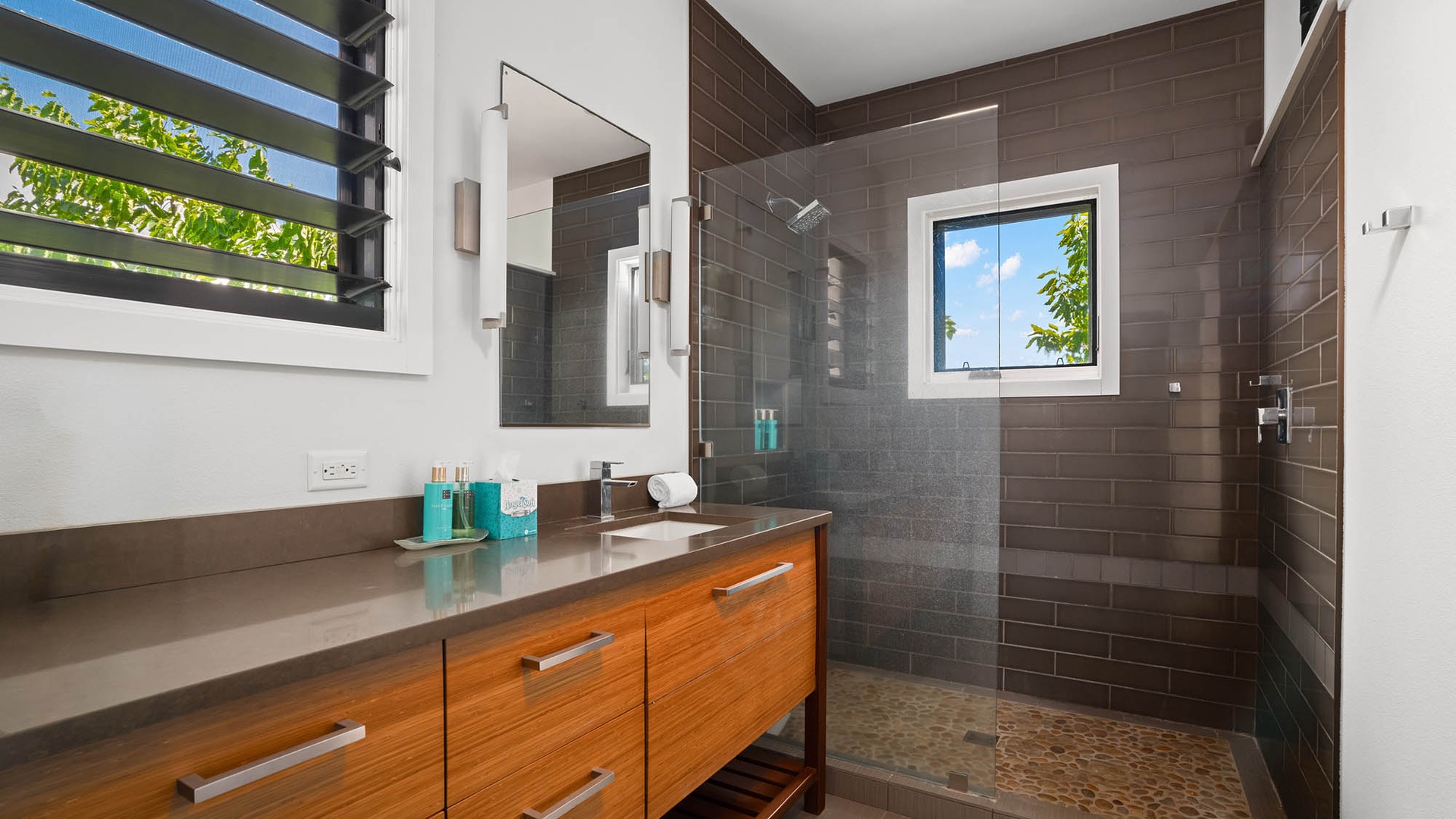 Your private bathroom features sleek tiling, a spacious walk-in shower, and warm wood vanity—perfect for refreshing after a day of adventure.