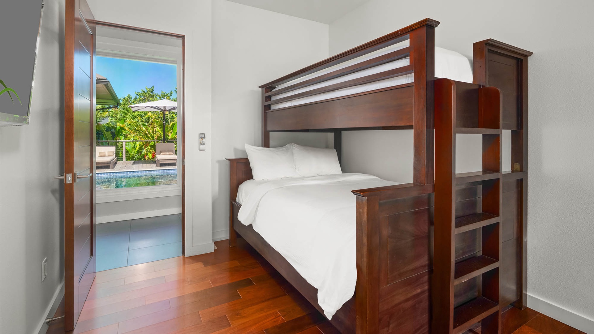 Sink into crisp linens and wake to a sparkling pool view just beyond your door—rich hardwood floors and warm wood tones make this serene retreat yours to enjoy.
