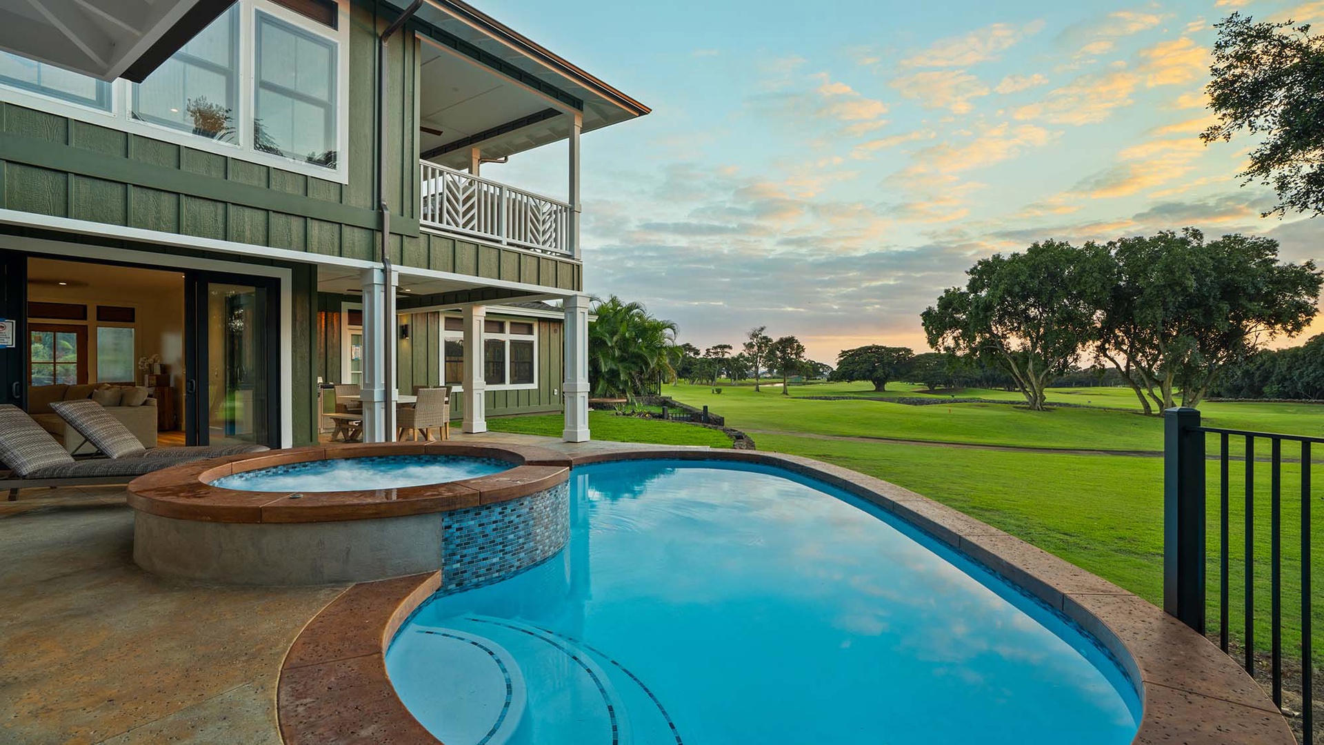 Modern vacation home with private pool and hot tub overlooking pristine golf course greens at sunset.
