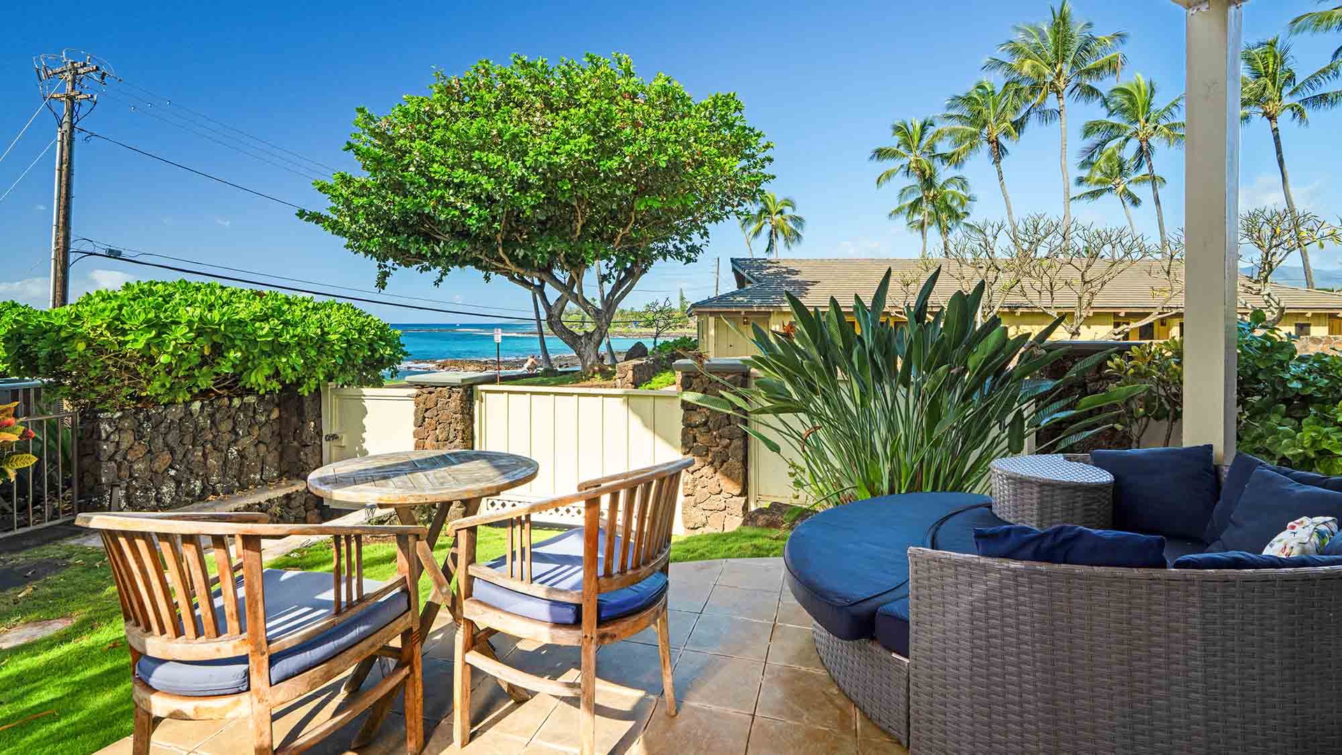 Relax on your private patio with comfortable seating while enjoying stunning ocean views framed by tropical palms.