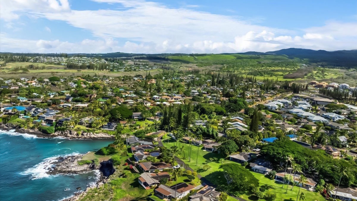Stunning aerial view of a tropical coastal community nestled between turquoise waters and lush green mountains.