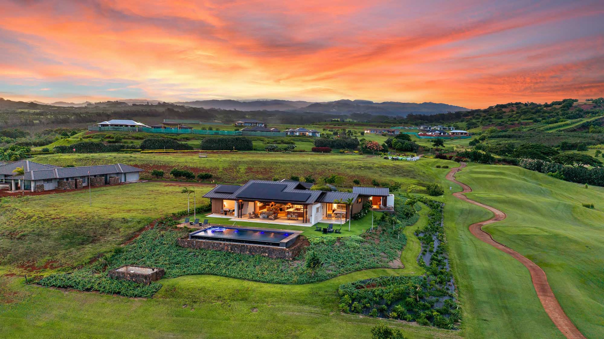 The property sits on an expansive golf course estate with mountain views, surrounded by rolling greens, natural landscape, and a dramatic sunset sky overhead.