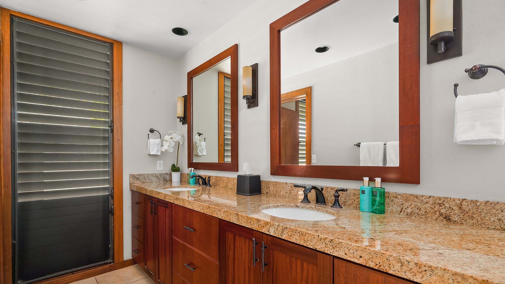 You'll love getting ready in this spacious dual-vanity bathroom, where warm wood tones meet elegant granite countertops and thoughtful touches await at every turn.