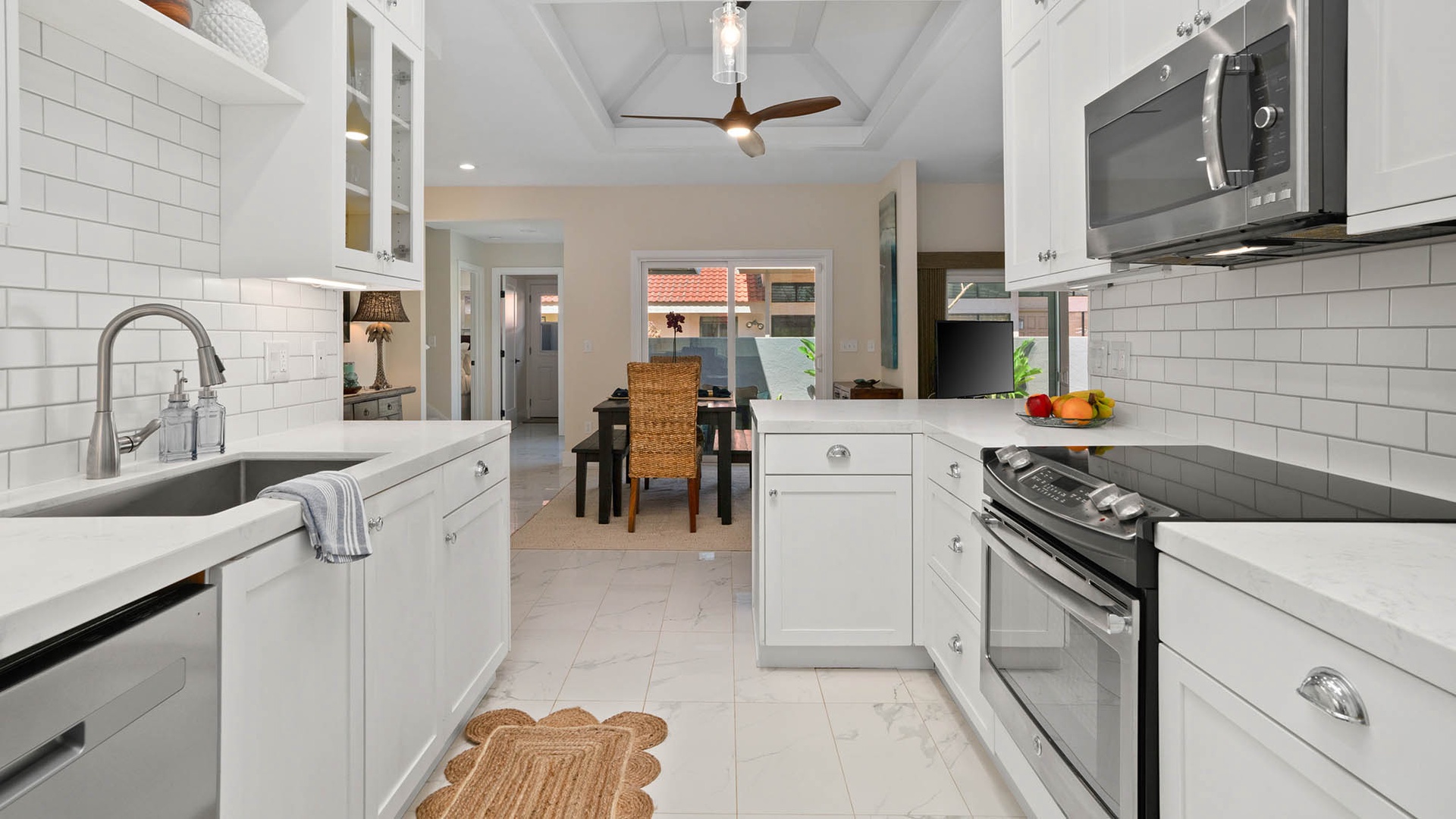Step into your gleaming white kitchen with subway tile, sleek counters, and modern appliances. Fresh fruit waits on the counter, and your dining table is just steps away.