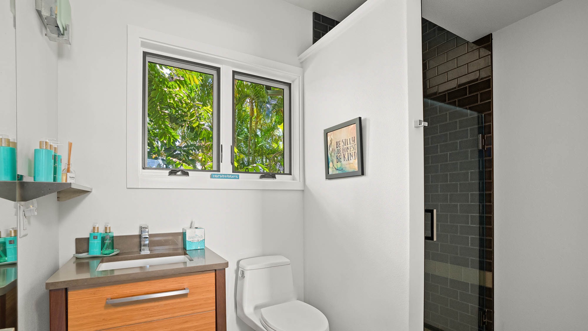 Your modern bathroom features a sleek vanity, subway-tiled shower, and tropical garden views that brighten the space with natural light.
