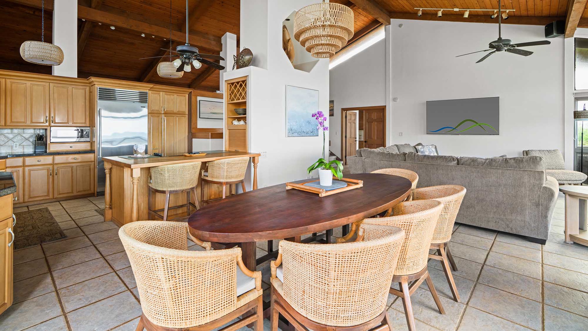 Gather around your elegant oval dining table where warm wood and wicker create the perfect space for memorable meals together.