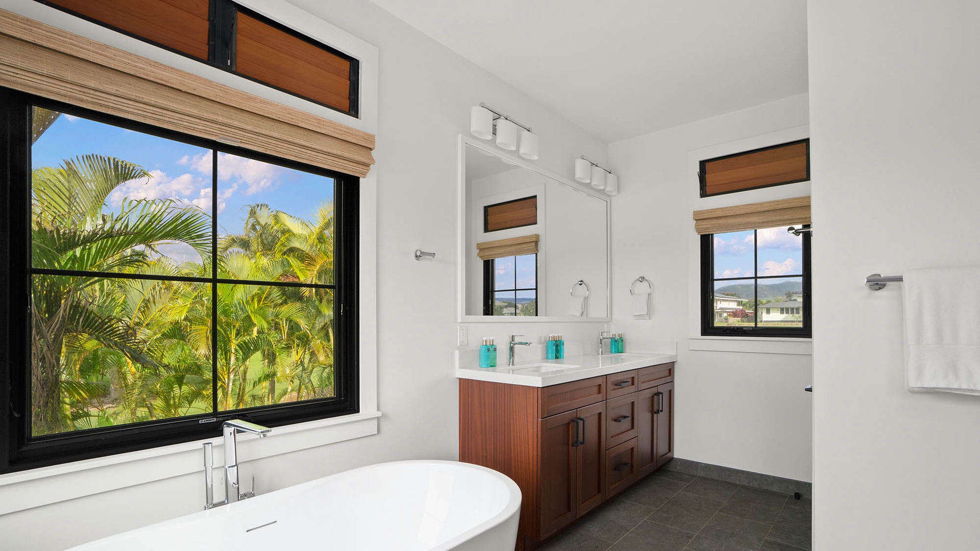Soak in your elegant bathroom featuring a luxurious soaking tub with tropical garden views through expansive windows.