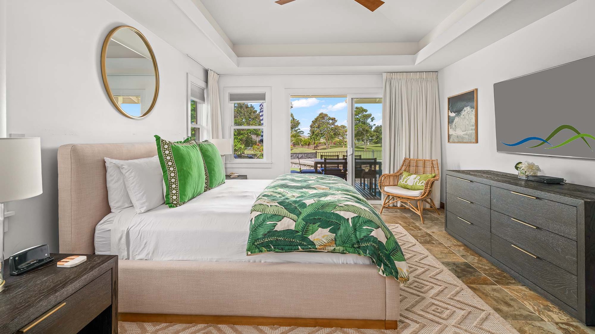 Unwind in this bright, restful bedroom with lush tropical bedding, cozy seating, and doors opening to your private balcony overlooking serene views—your peaceful retreat awaits.
