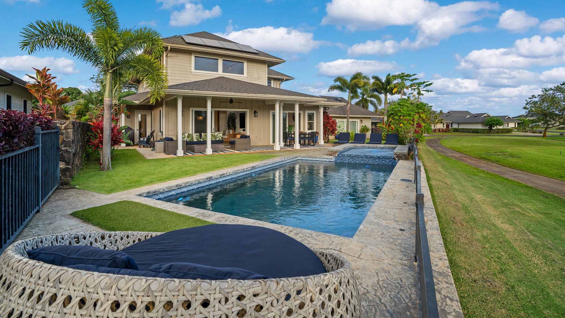 This beautiful vacation home features a spacious backyard with a private pool, lush tropical landscaping, and covered lanai perfect for relaxing after a day of island adventures.