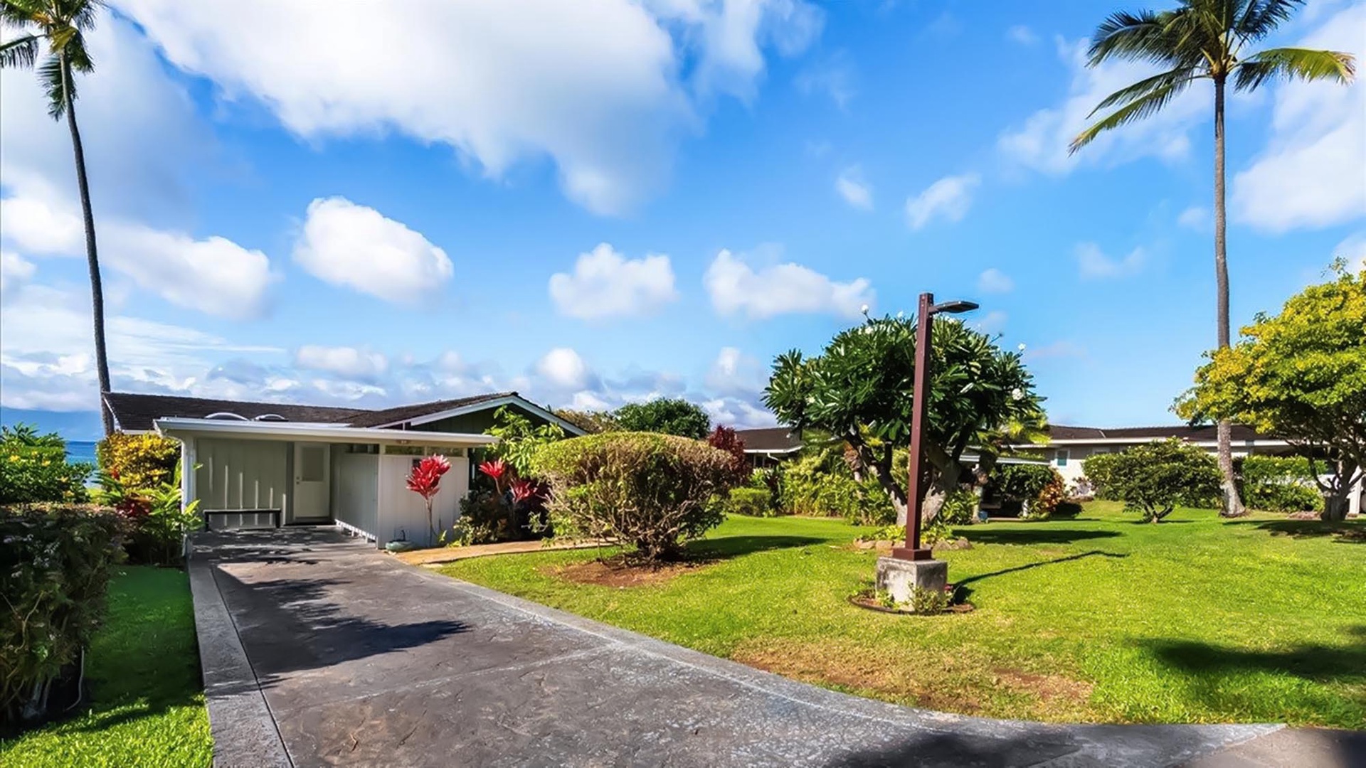Tropical paradise with lush landscaping, towering palms, and ocean views creates the perfect Hawaiian getaway backdrop.