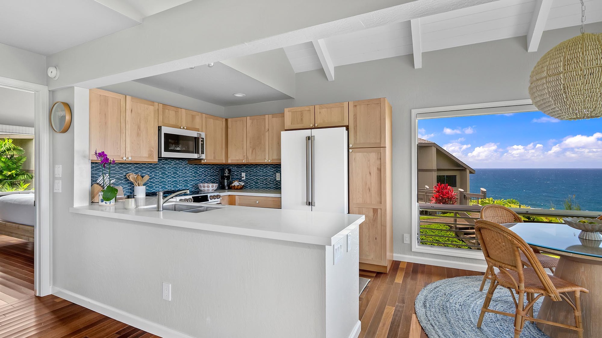 Your bright, modern kitchen opens to stunning ocean views through expansive glass doors, inviting you to cook while soaking in the coastal beauty and gentle sea breezes.