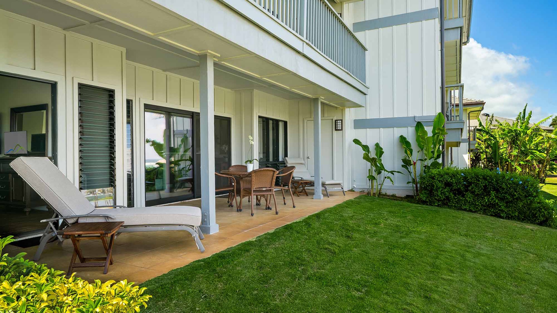 Relax on your private patio with a lounge chair and dining set, overlooking manicured lawn and tropical greenery—perfect for morning coffee or sunset dinners.