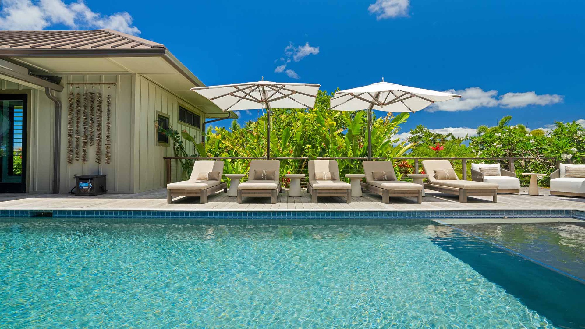 Slip into crystal-clear waters or lounge poolside under a tropical sky—your private paradise awaits, complete with lush greenery and cushioned sunbeds shaded by elegant umbrellas.