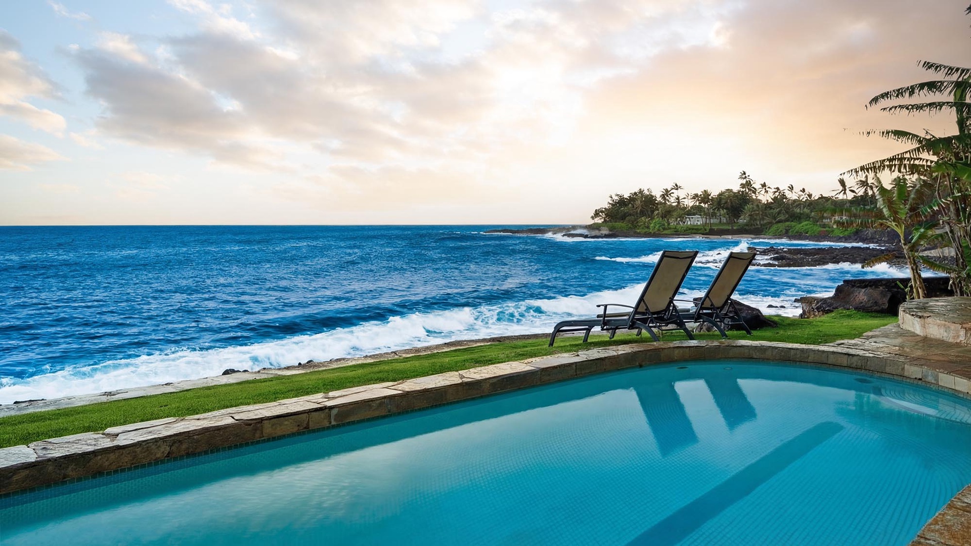 Stunning oceanfront infinity pool with turquoise water mirrors tropical paradise, while comfortable loungers await your relaxation by the sea.