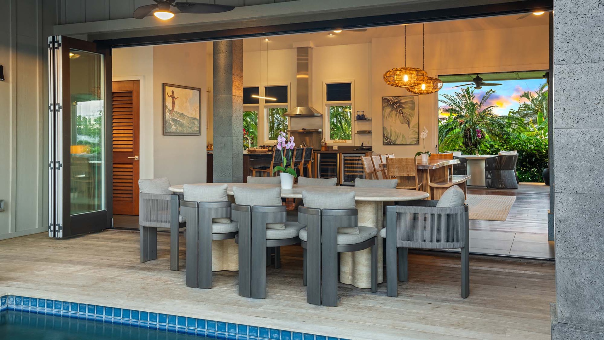 Poolside living flows seamlessly between indoors and out, with a stylish dining area and open kitchen bathed in warm evening light—your perfect spot for tropical gatherings.