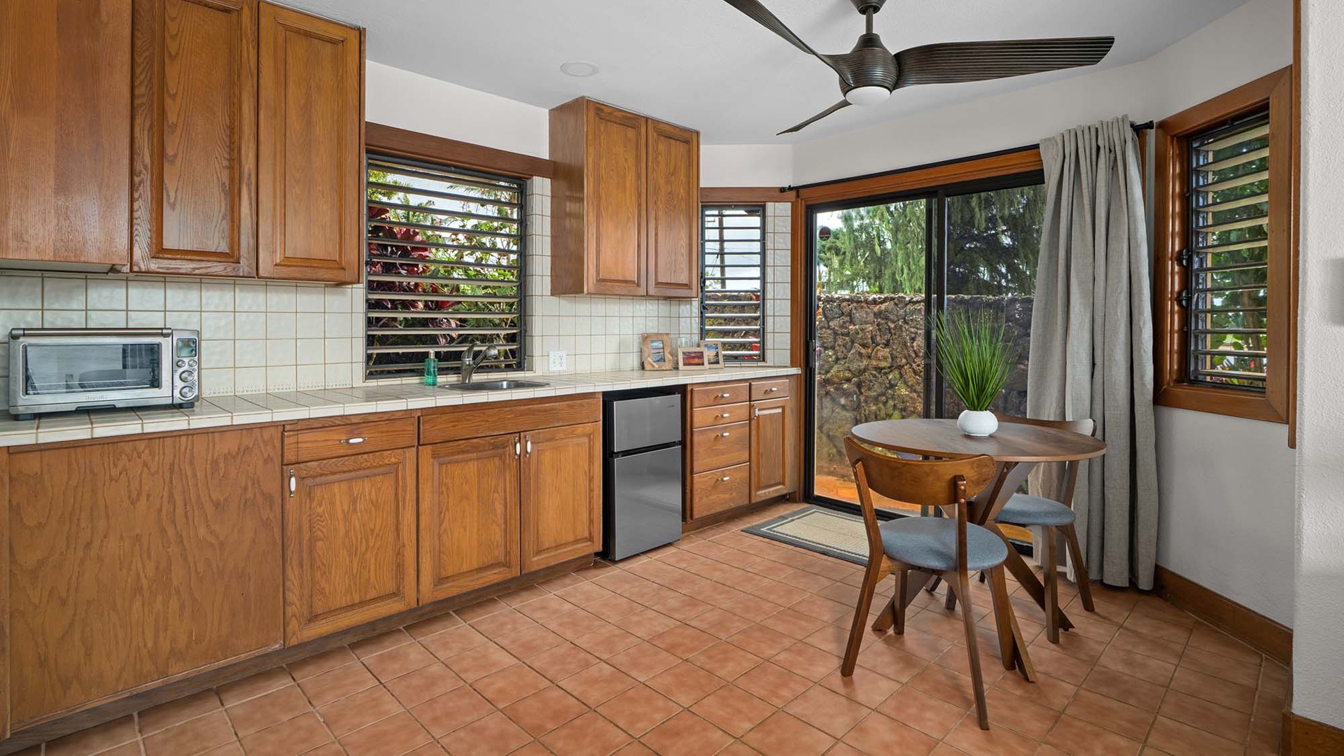 Your fully equipped kitchen awaits with warm wood cabinetry, modern appliances, and a cozy dining nook where you can savor morning coffee while enjoying garden views.