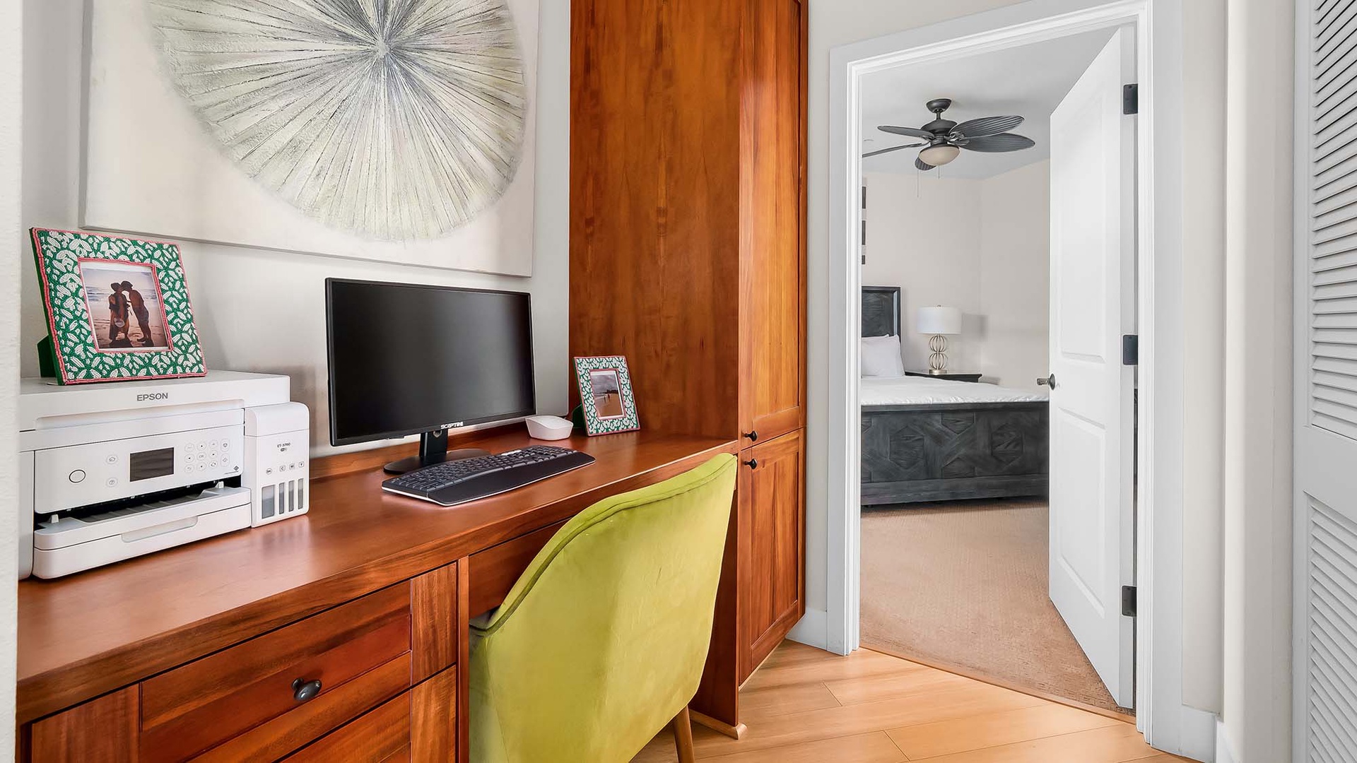 Your workspace opens to a serene bedroom with a unique dresser and ceiling fan to keep things cool.