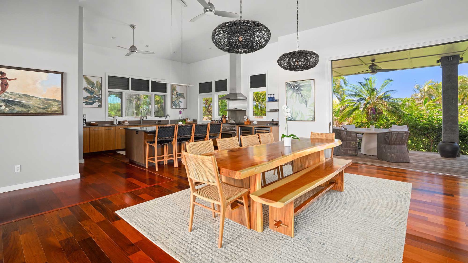Step into your tropical haven where rich hardwood floors meet island-style elegance. Gather around the handcrafted dining table while natural breezes drift through open walls, connecting you to lush palm views and endless relaxation.