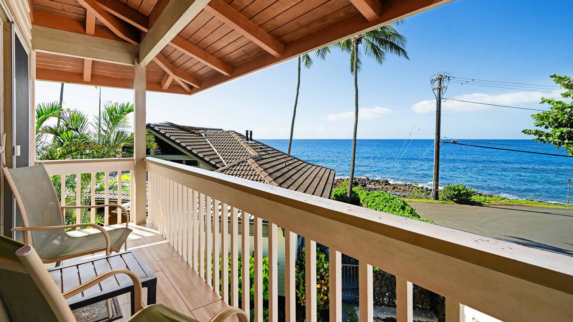 Tropical covered balcony with stunning ocean views across azure waters and swaying palm trees.