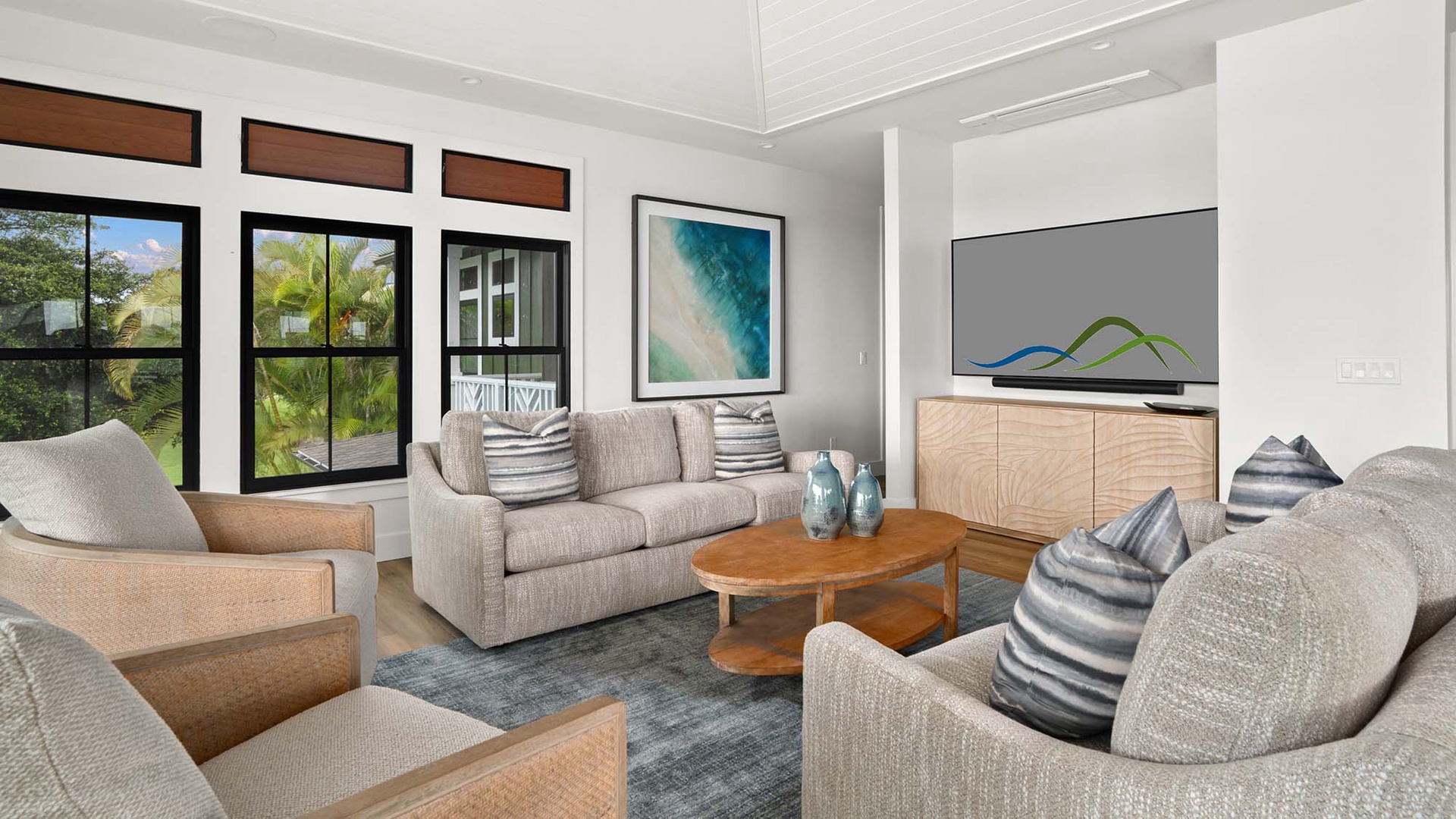 Relax in your stylish living space featuring coastal artwork, comfortable seating, and warm natural light streaming through tropical garden views.