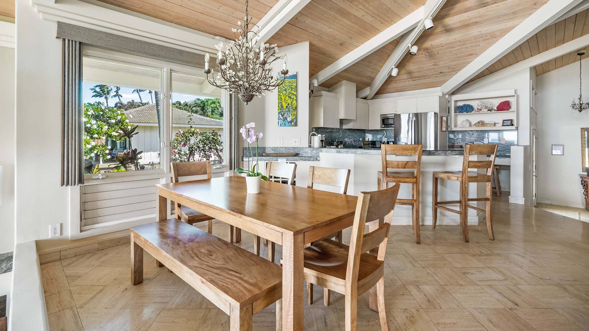 Gather around this inviting dining table where your group can enjoy meals together, bathed in natural light from large windows overlooking the garden. The open flow to the modern kitchen makes it easy to cook, serve, and create lasting memories.