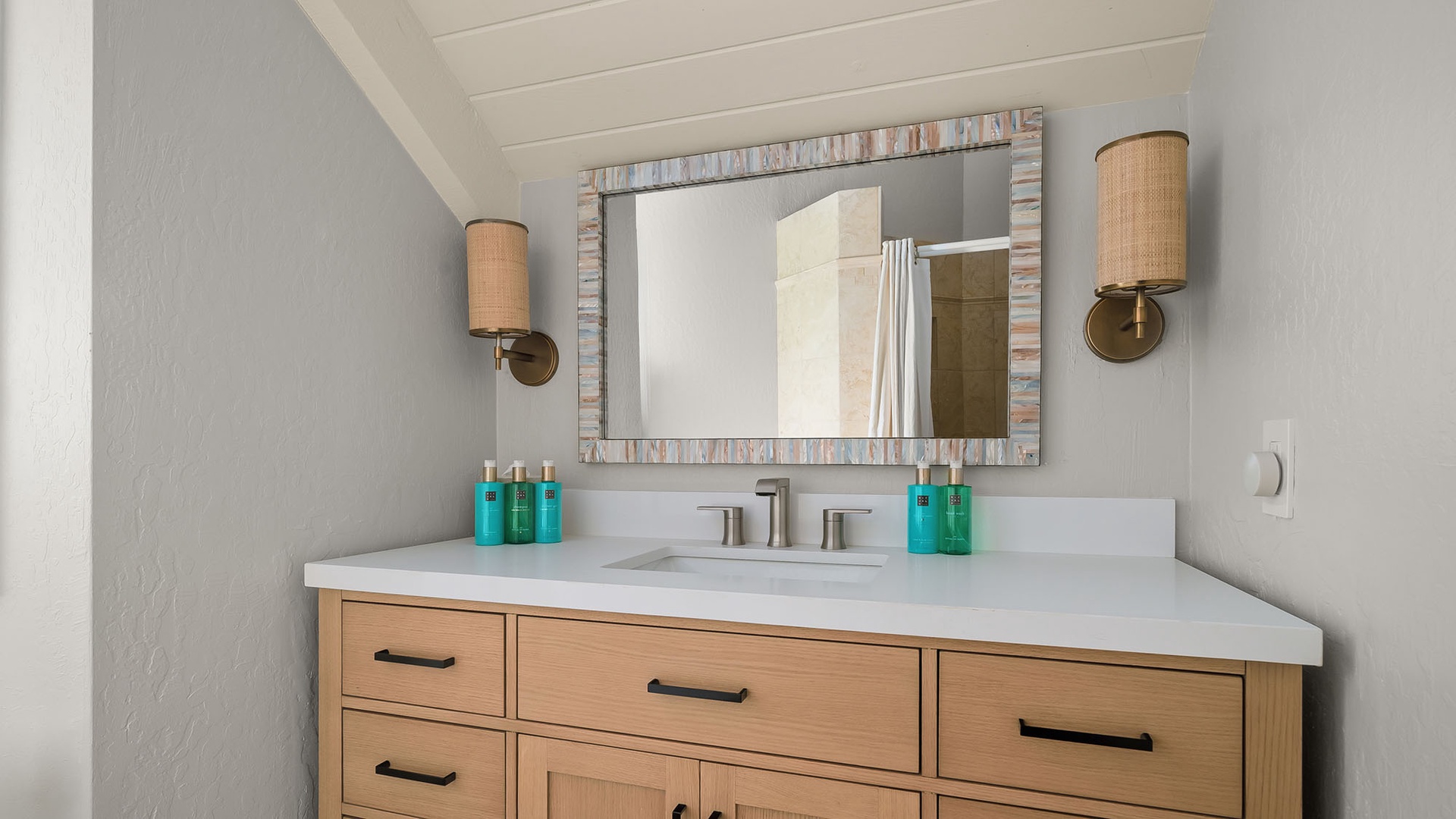 You'll love this stylish vanity space, where warm wood tones meet serene coastal blues. Soft sconces glow above, creating the perfect lighting for your morning routine.
